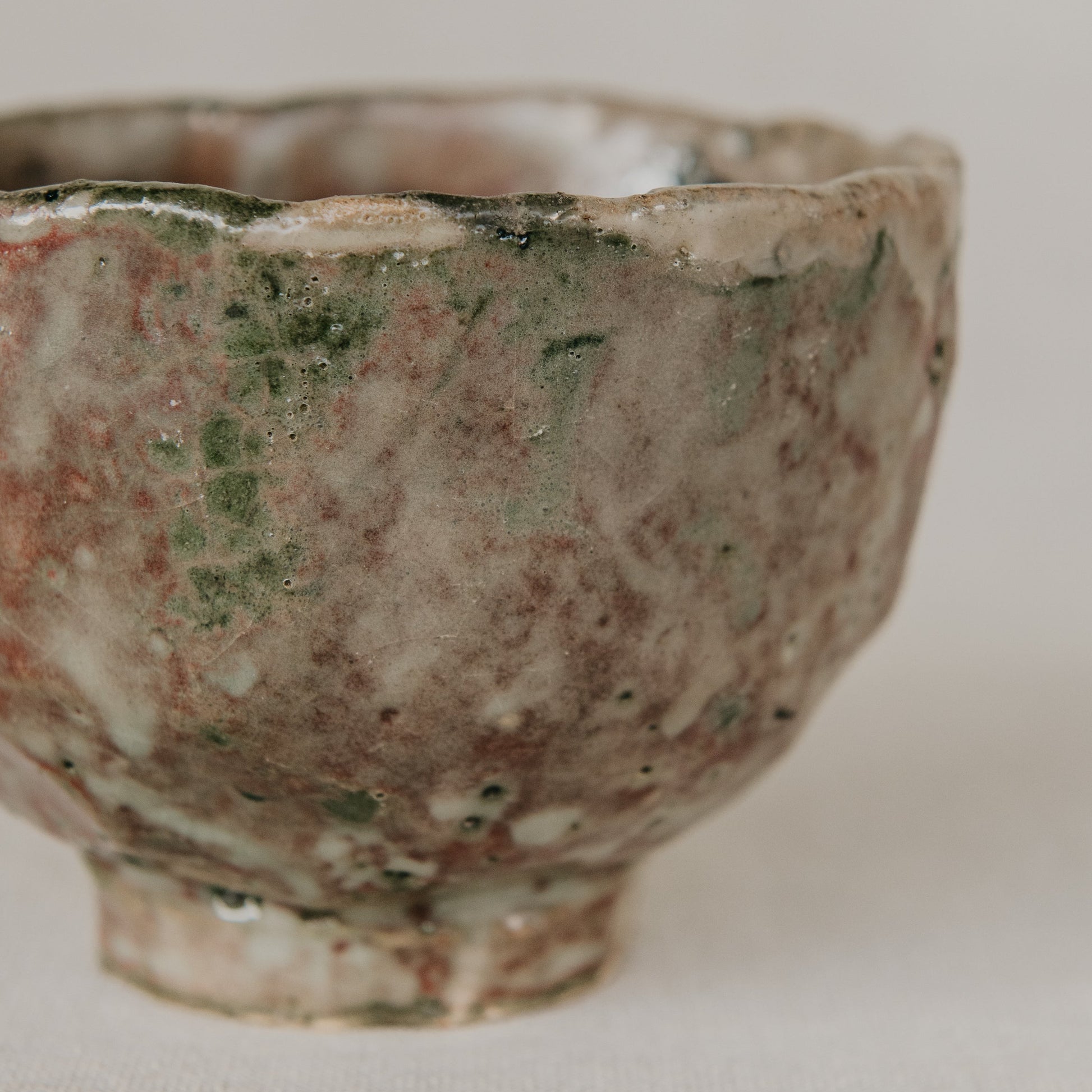 Vintage ceramic bowl with green and brown glaze on a white background