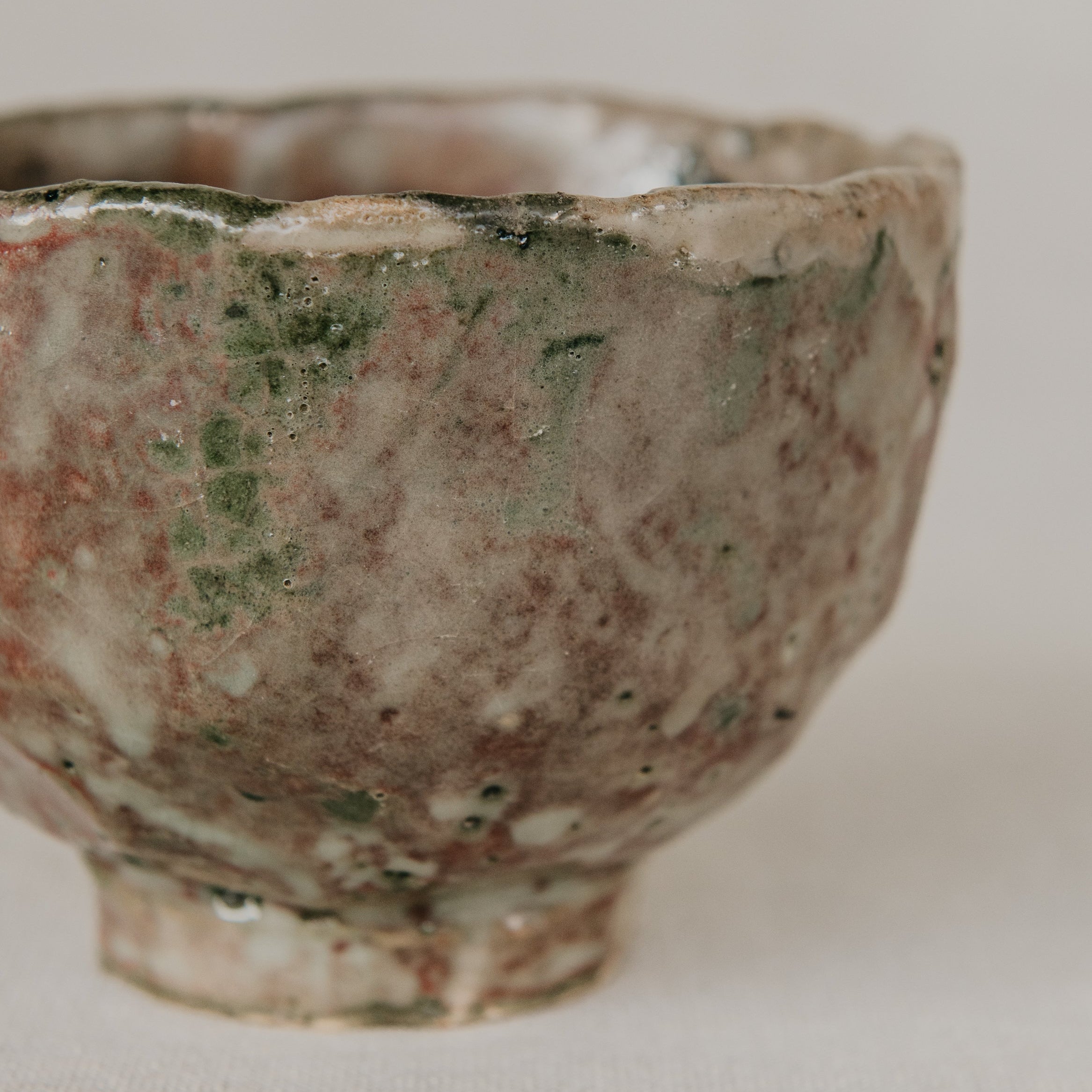 Vintage ceramic bowl with green and brown glaze on a white background