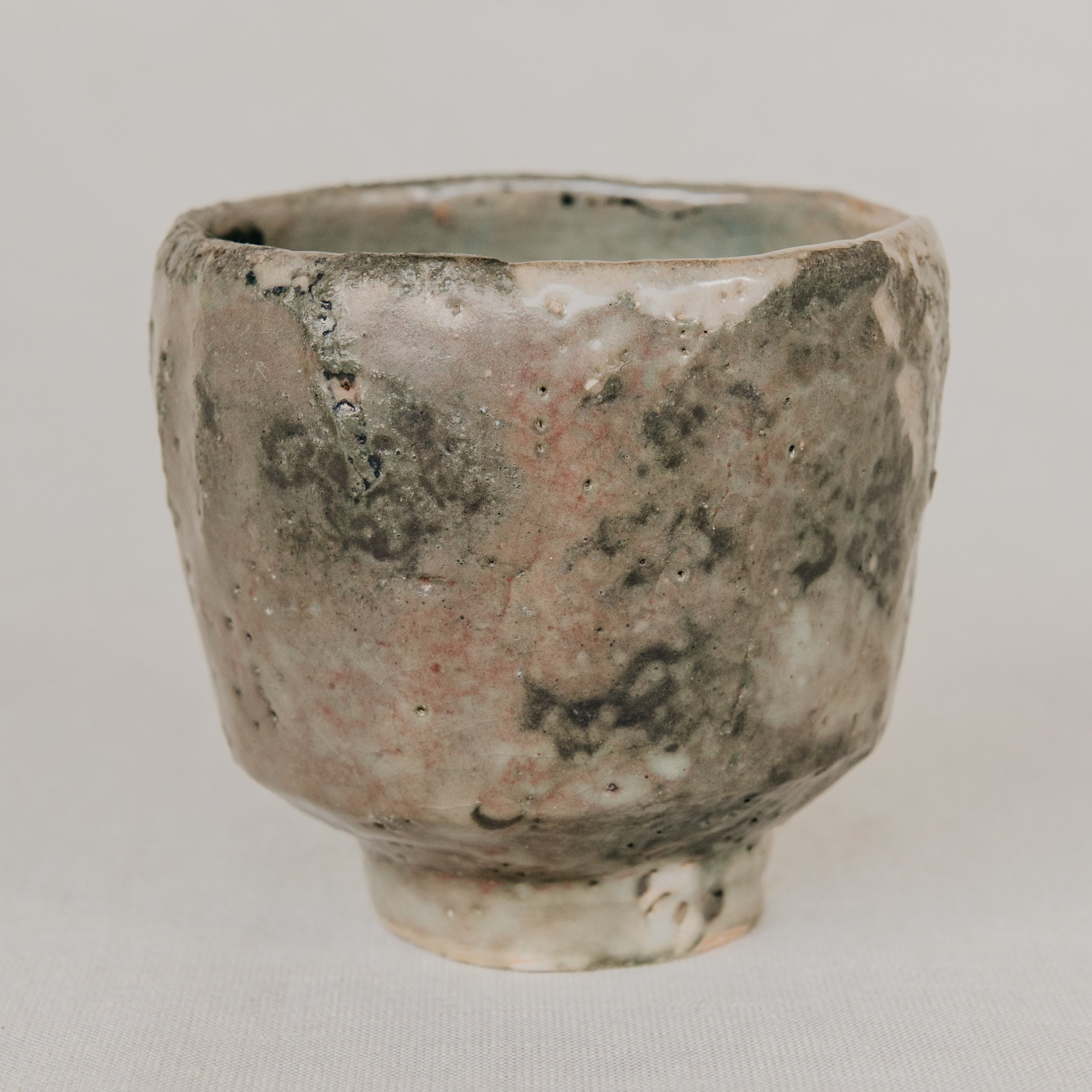 Small ceramic cup with a textured surface on a light gray background
