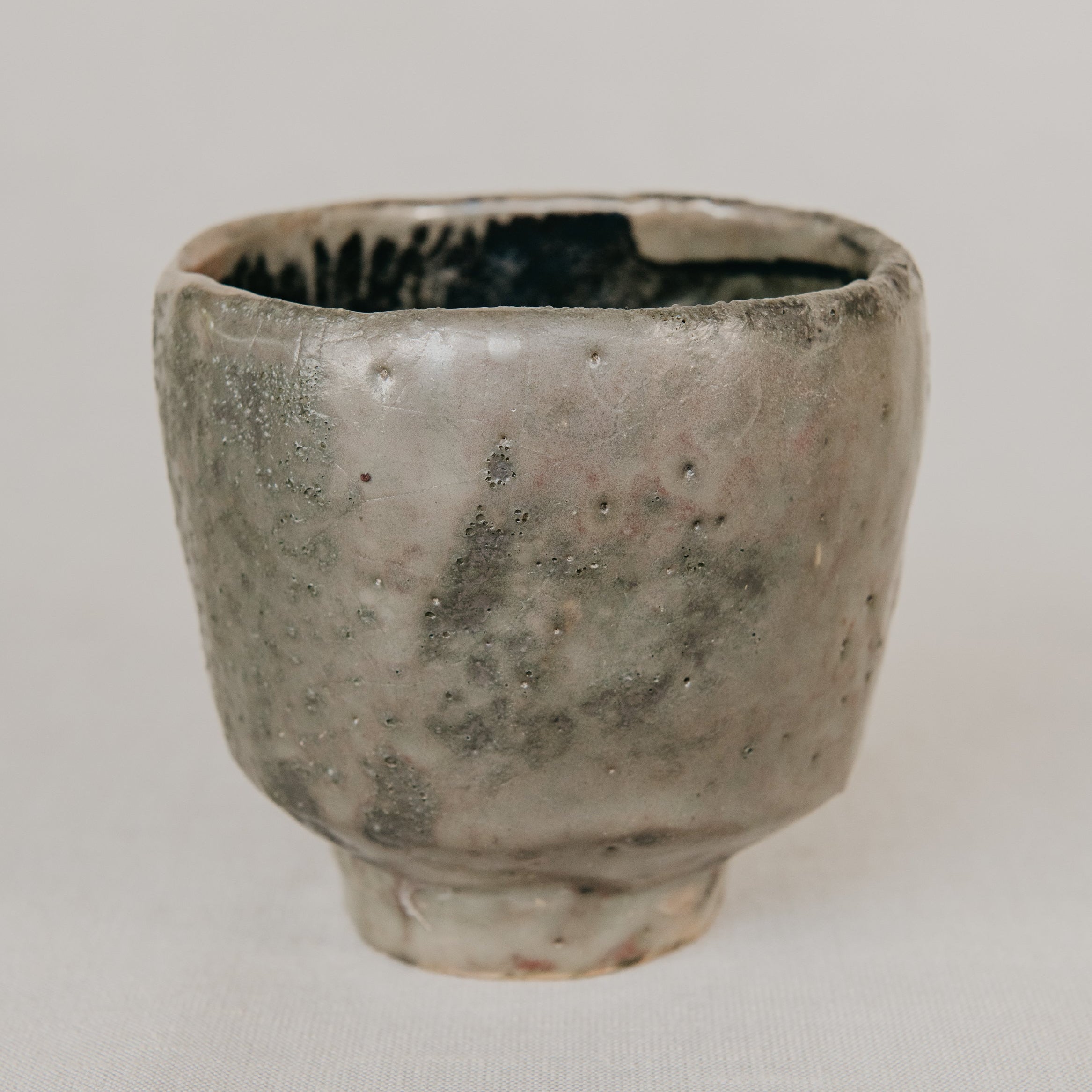 Vintage ceramic cup with a textured surface on a plain background
