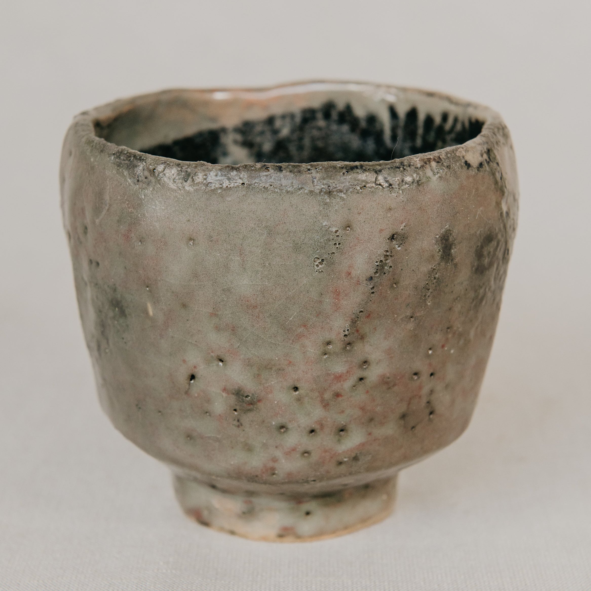 Small ceramic cup with a textured surface on a plain background