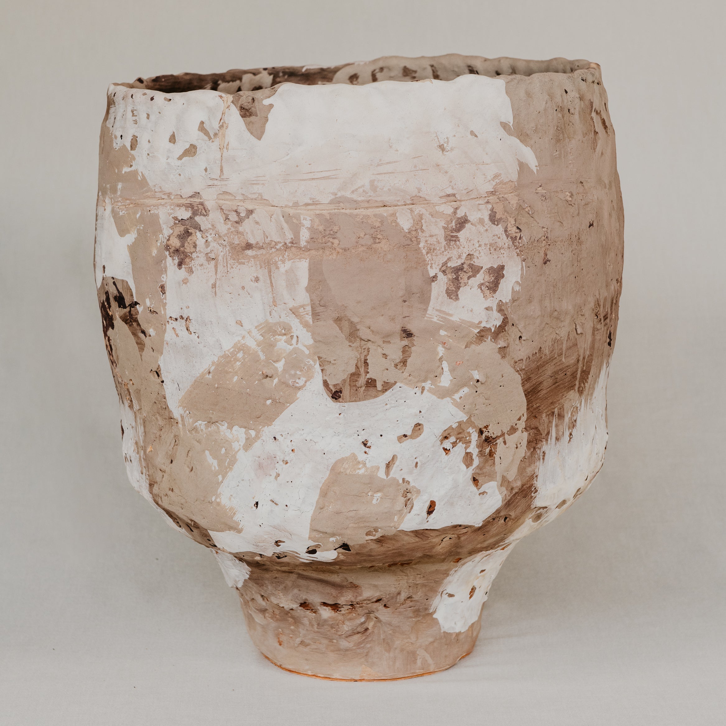 Terracotta pot with a textured surface on a plain background
