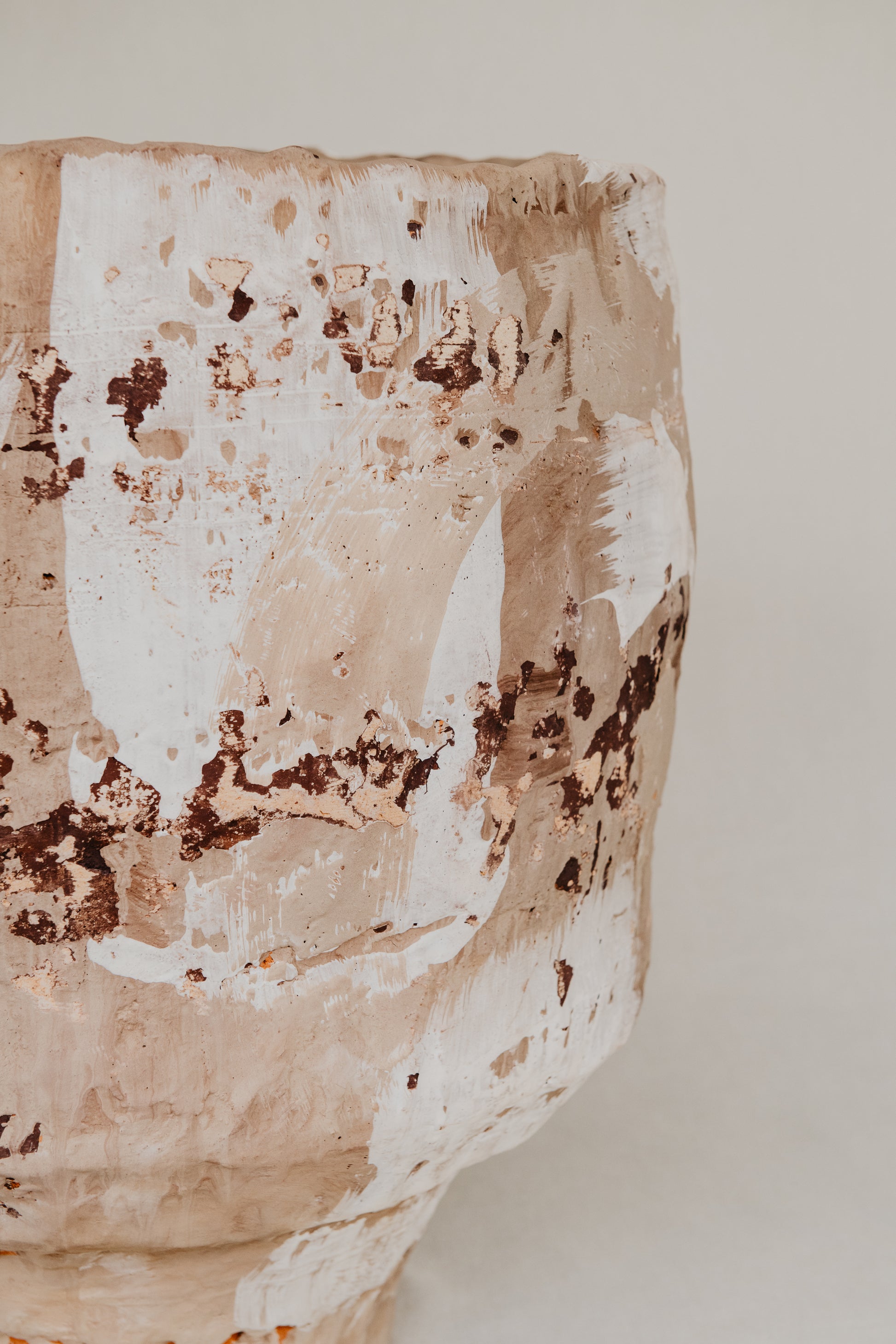 Close-up of a textured ceramic vase with brown and white patterns on a plain background