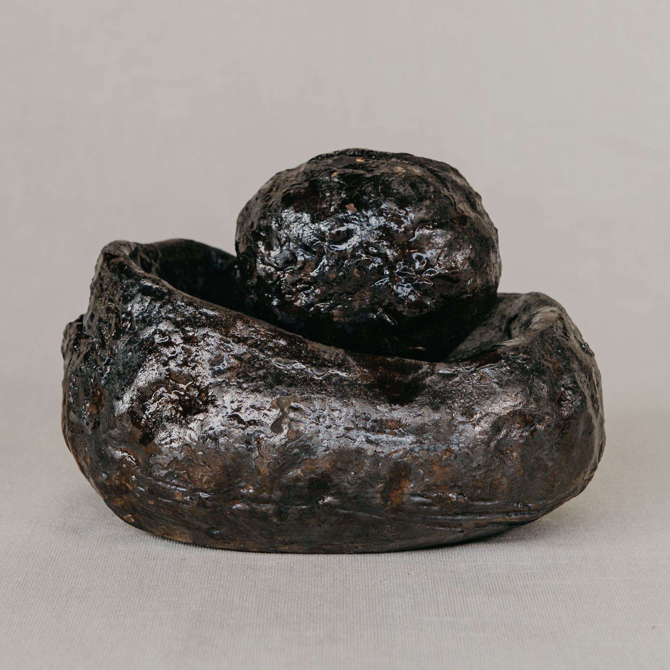 Rustic ceramic planter with a spherical object on a neutral background