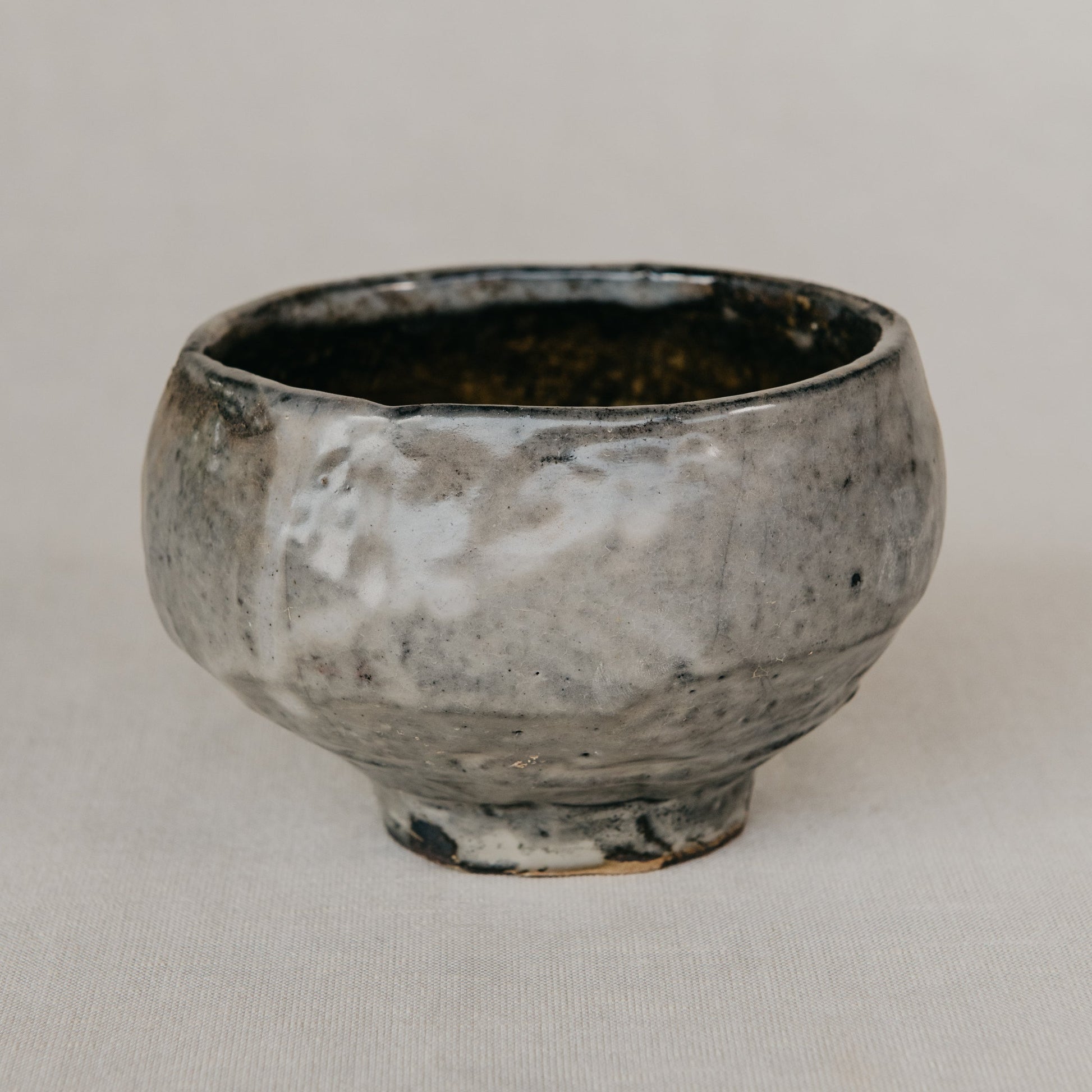 Small ceramic cup with a textured surface on a plain background