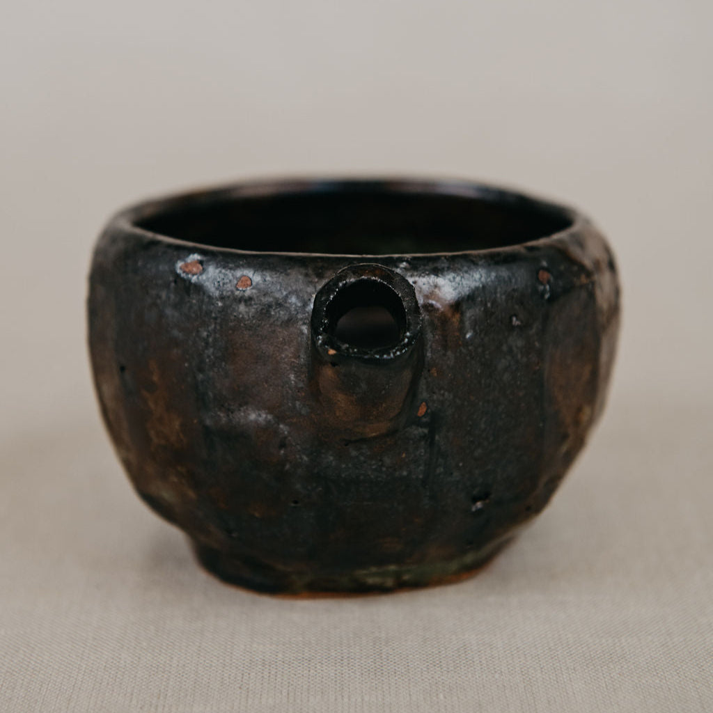Black ceramic cup with a handle on a beige background