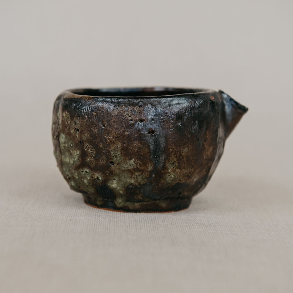 Rustic ceramic cup with a handle on a beige background