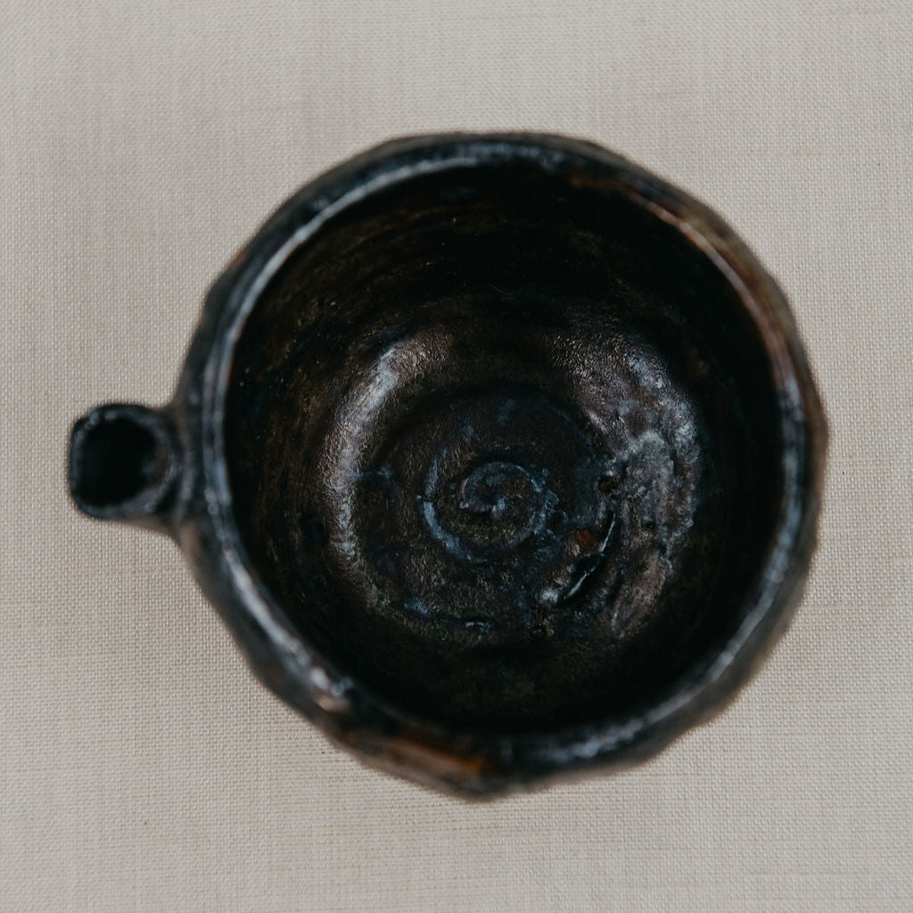 Black ceramic cup with spiral design on a beige background