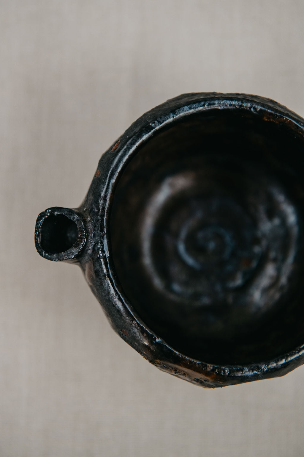 Close-up of a black ceramic vase with a textured surface on a neutral background