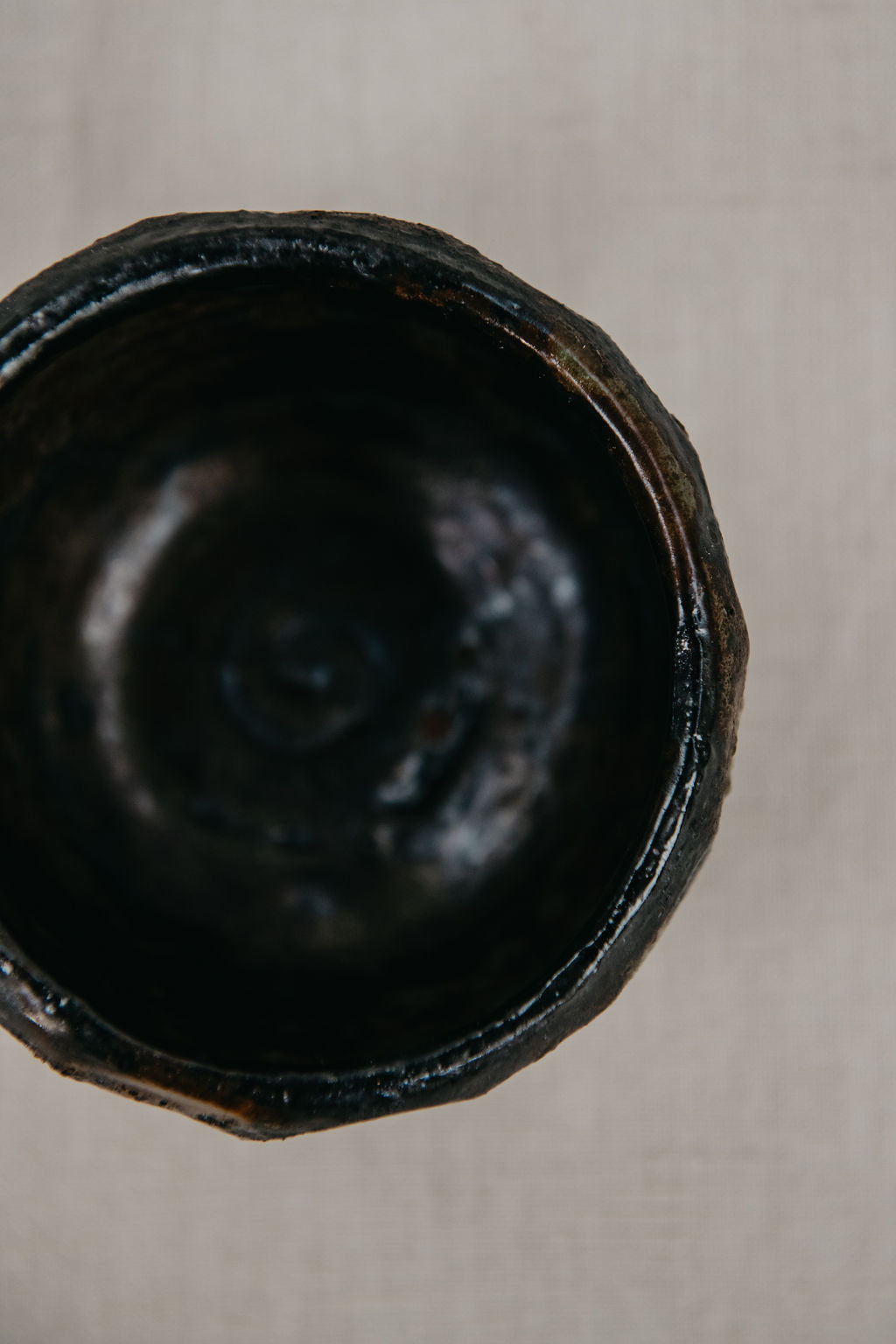 Close-up of a dark brown ceramic bowl on a light beige background