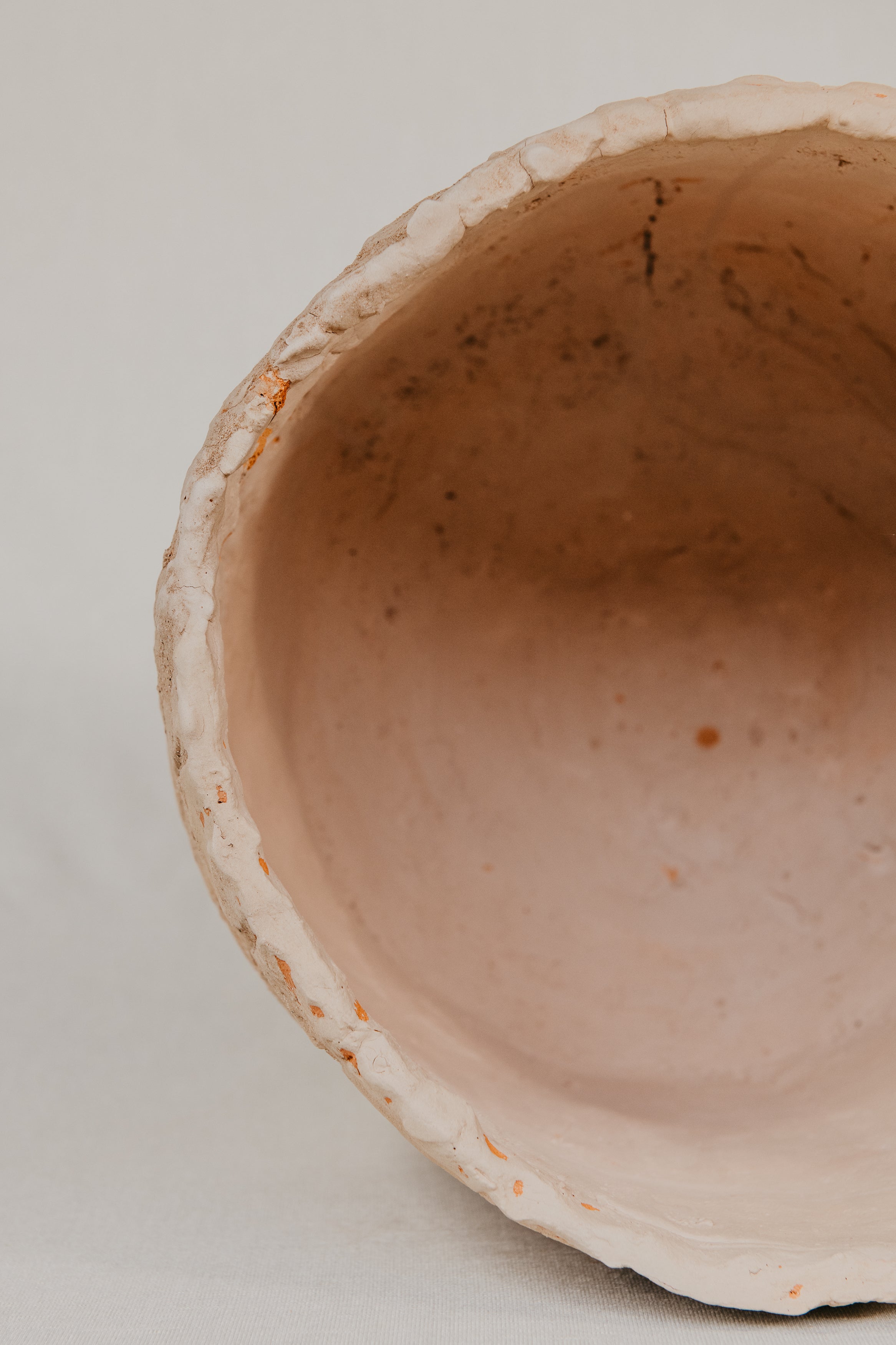 Close-up of a ceramic bowl with a textured edge on a light background