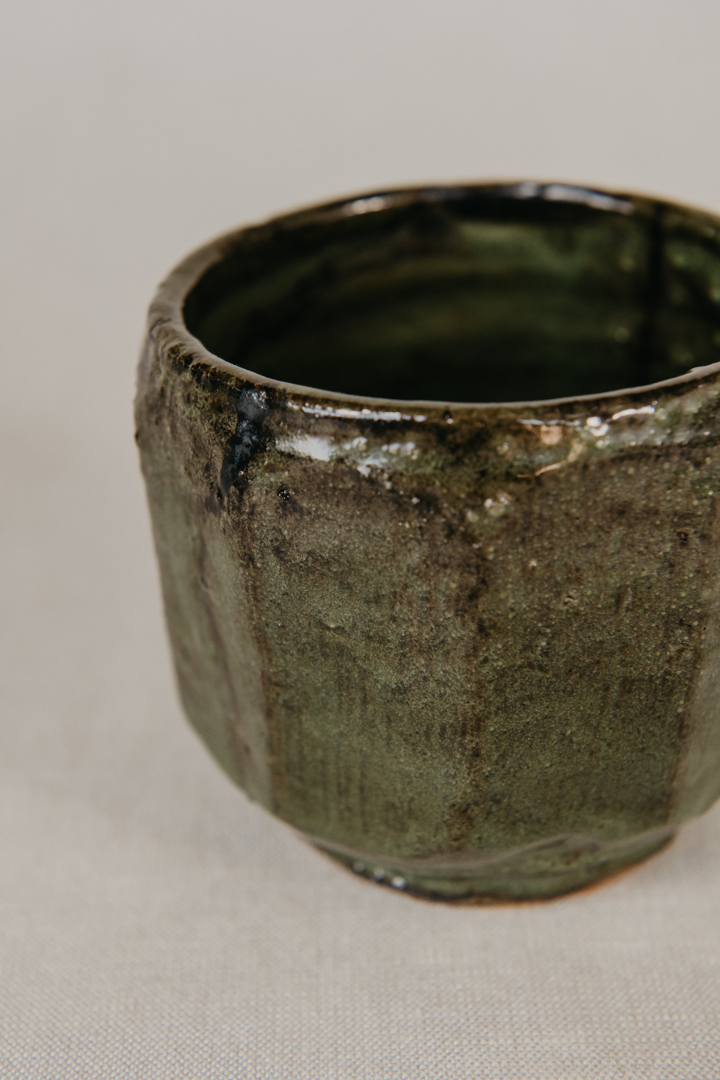 Green ceramic cup with textured surface on a light gray background