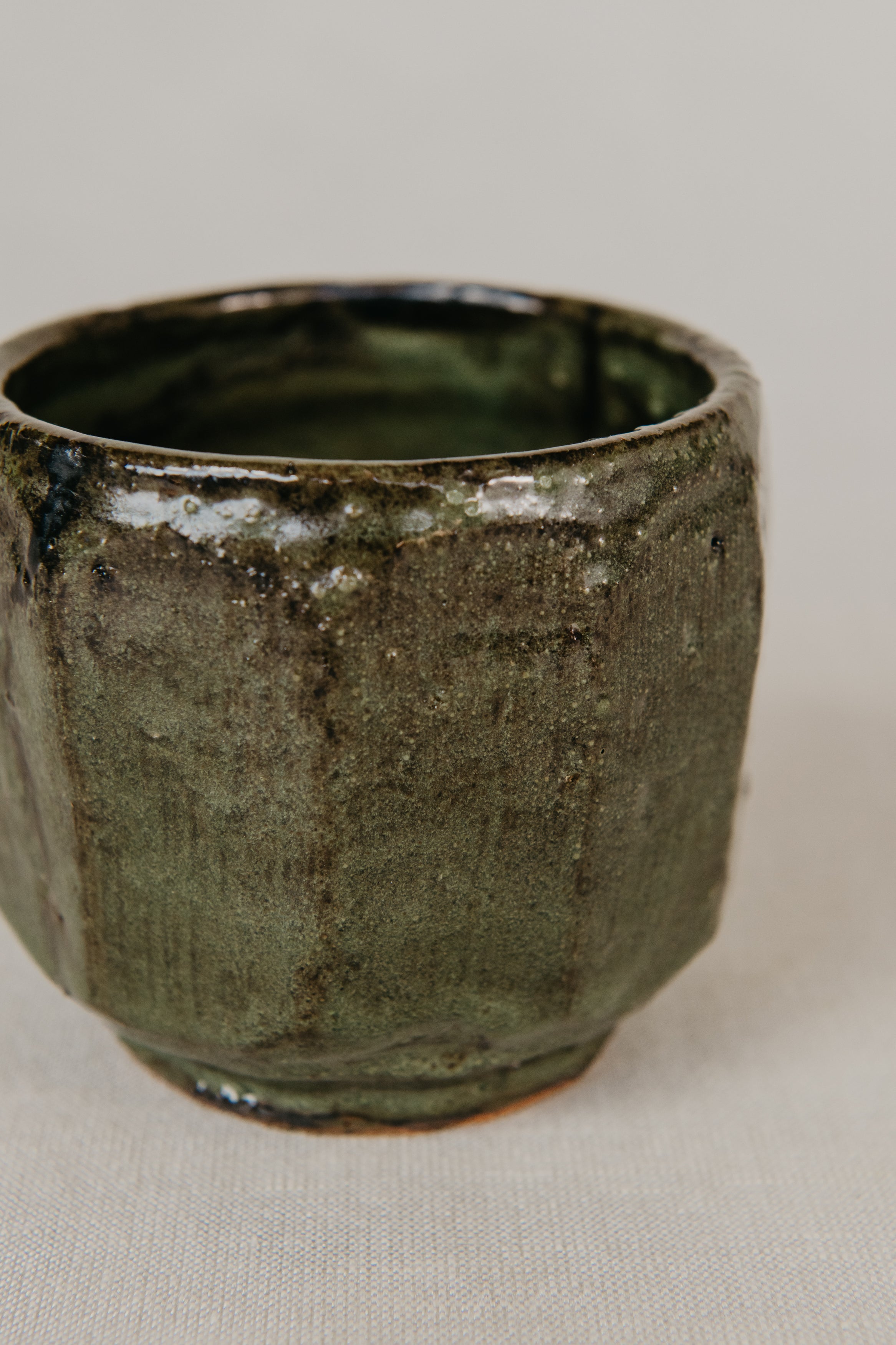 Green ceramic cup on a light beige background