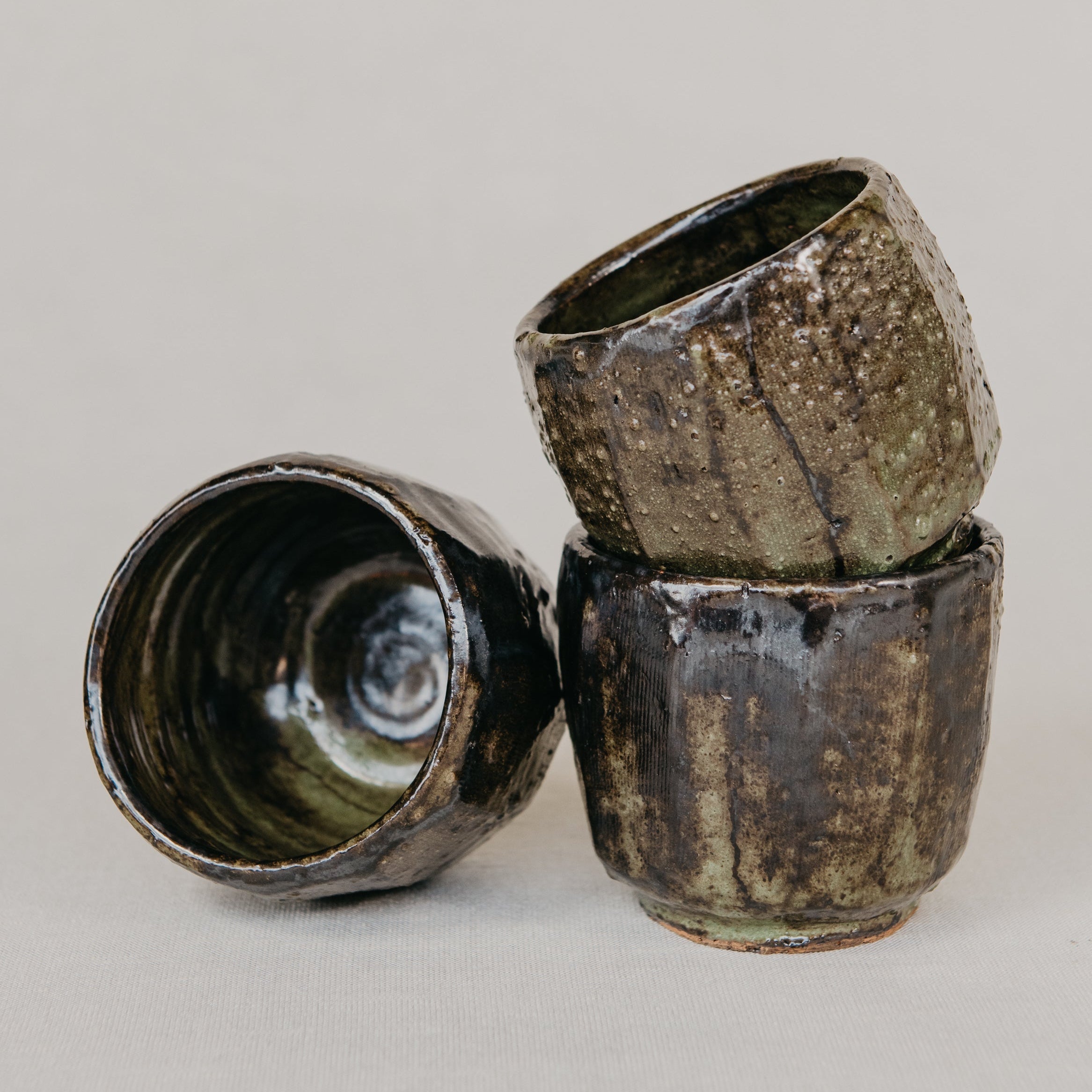 Three ceramic cups with a textured surface on a gray background
