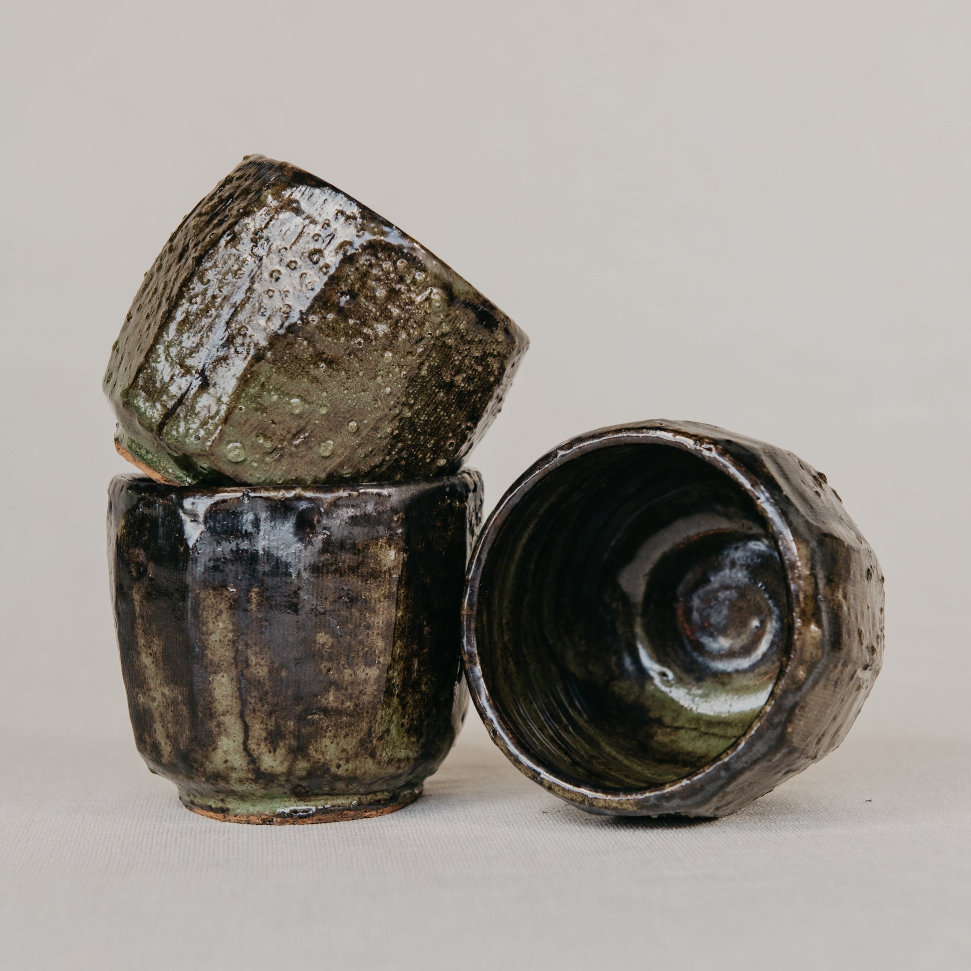 Three ceramic cups with textured surfaces on a light gray background