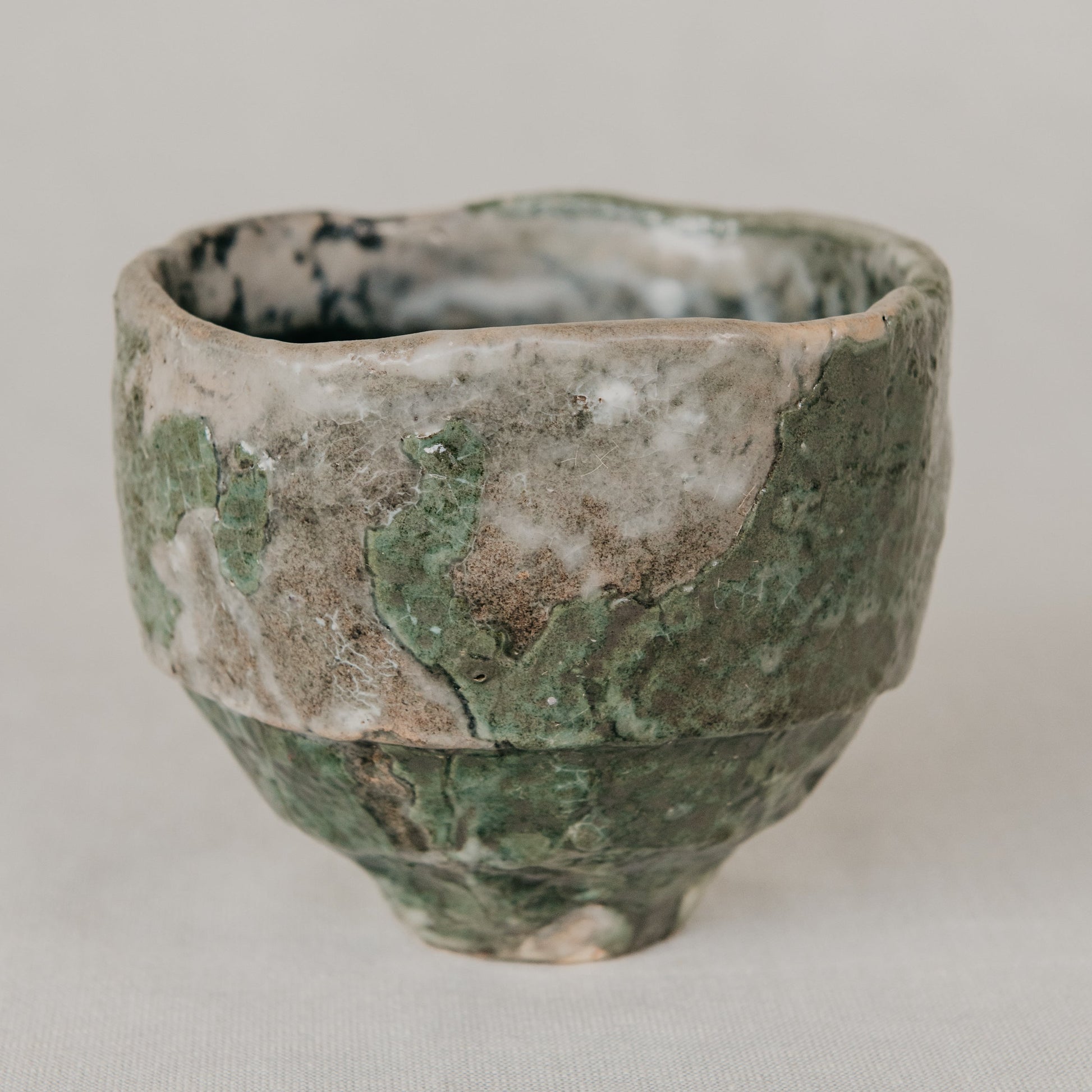 Green ceramic cup with textured surface on a light gray background