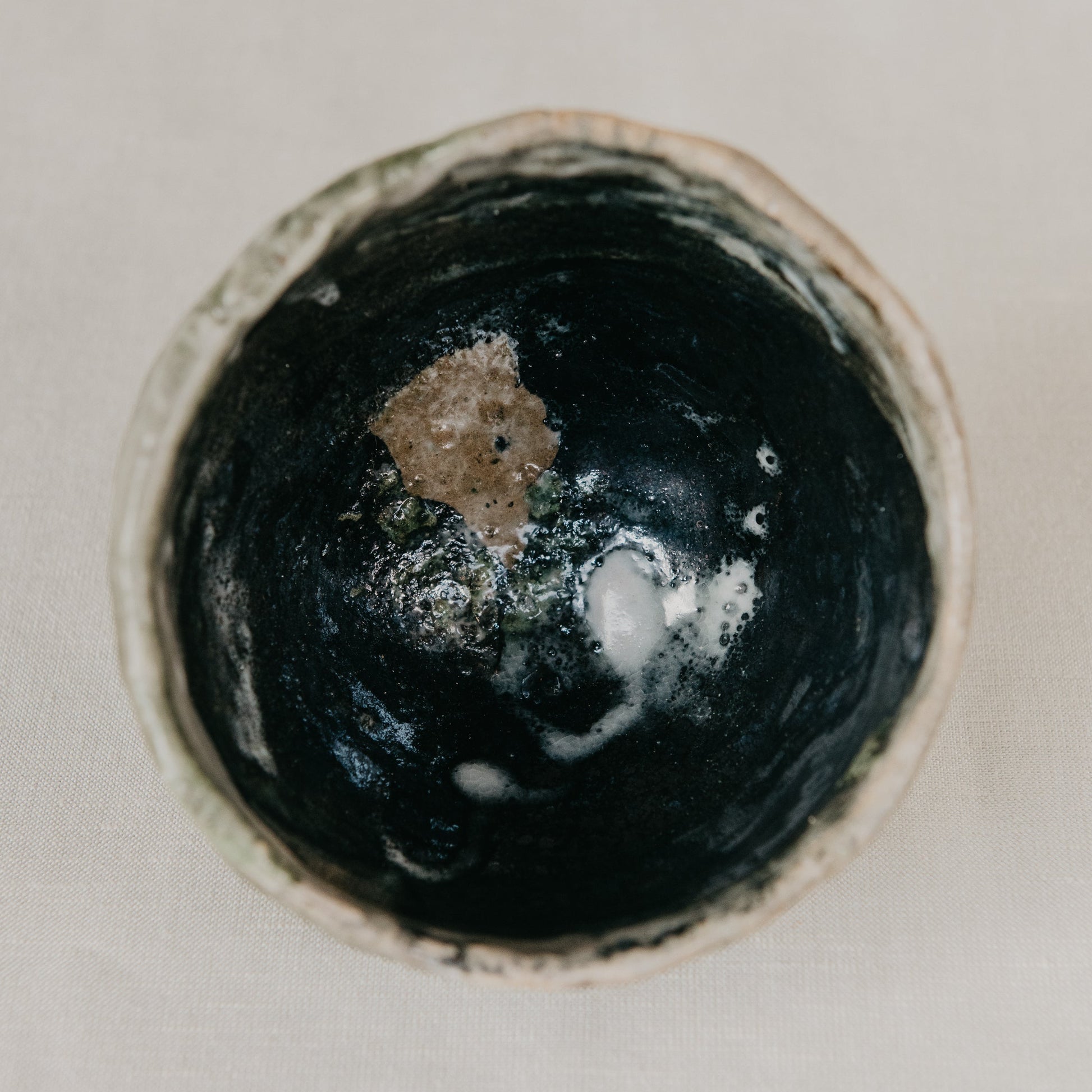 Close-up of a dark ceramic bowl with a textured surface on a light background