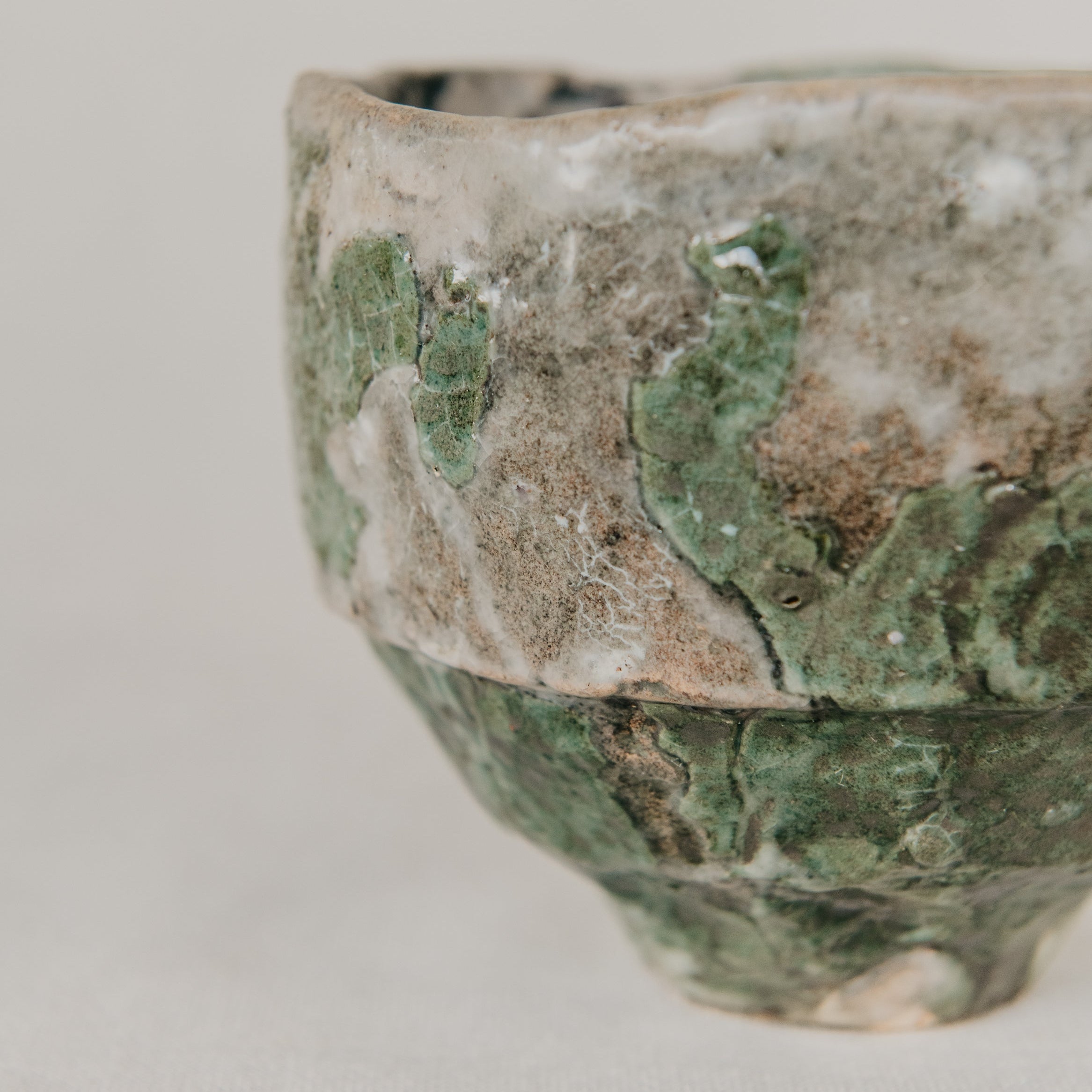 Vintage ceramic bowl with green glaze on a light gray background