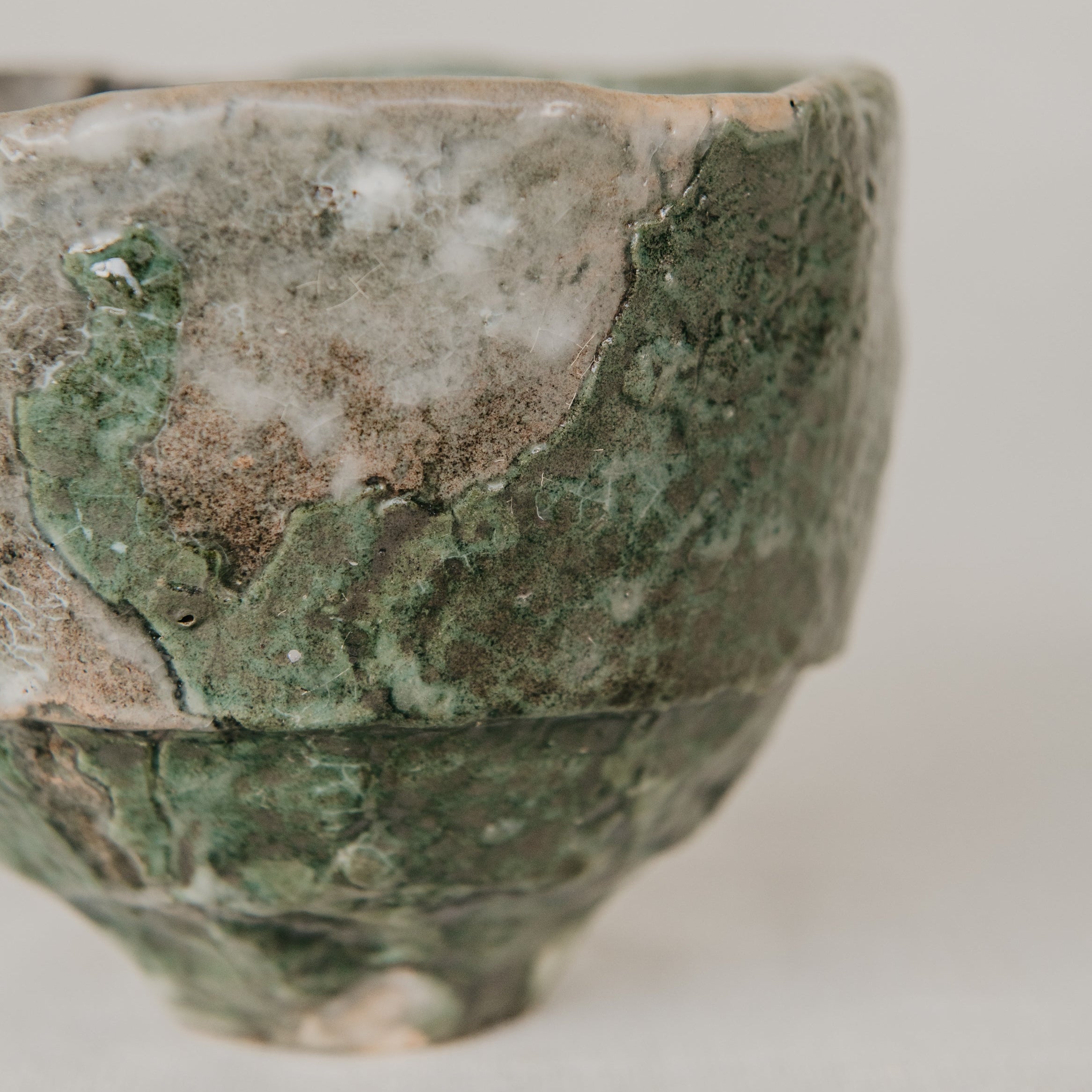 Green ceramic bowl with textured surface on a light gray background