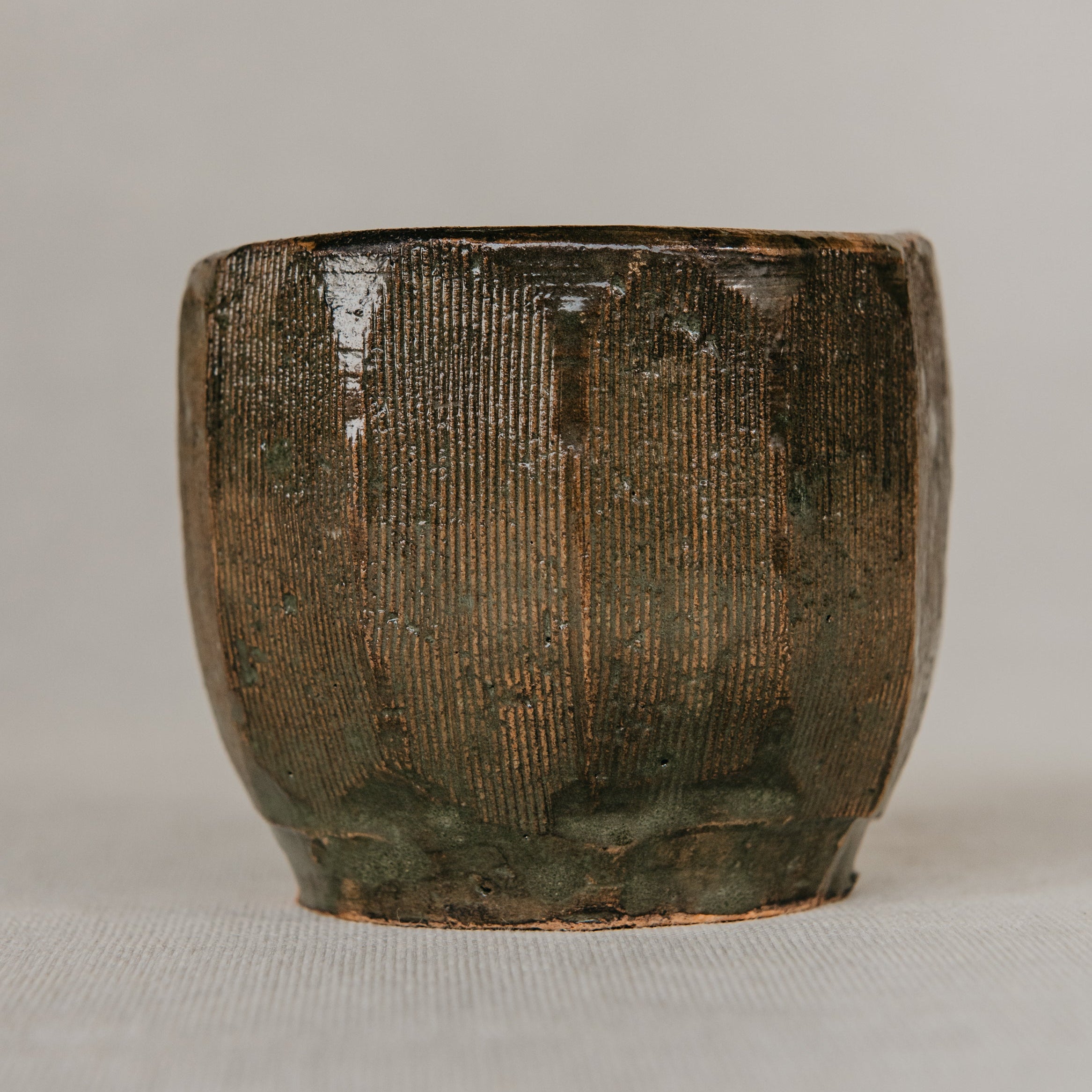 Brown ceramic cup with textured surface on a light gray background
