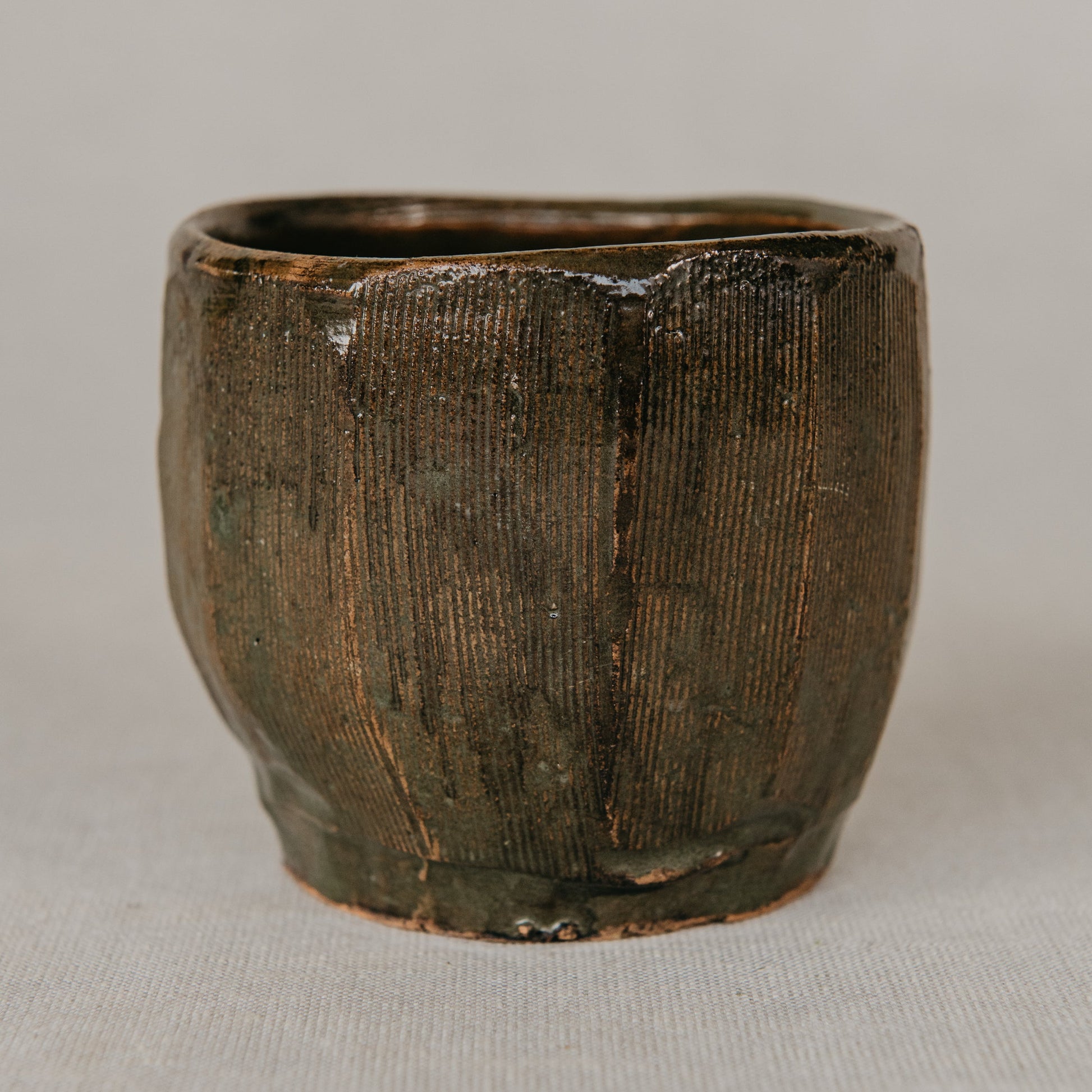 Brown ceramic cup with textured surface on a light gray background