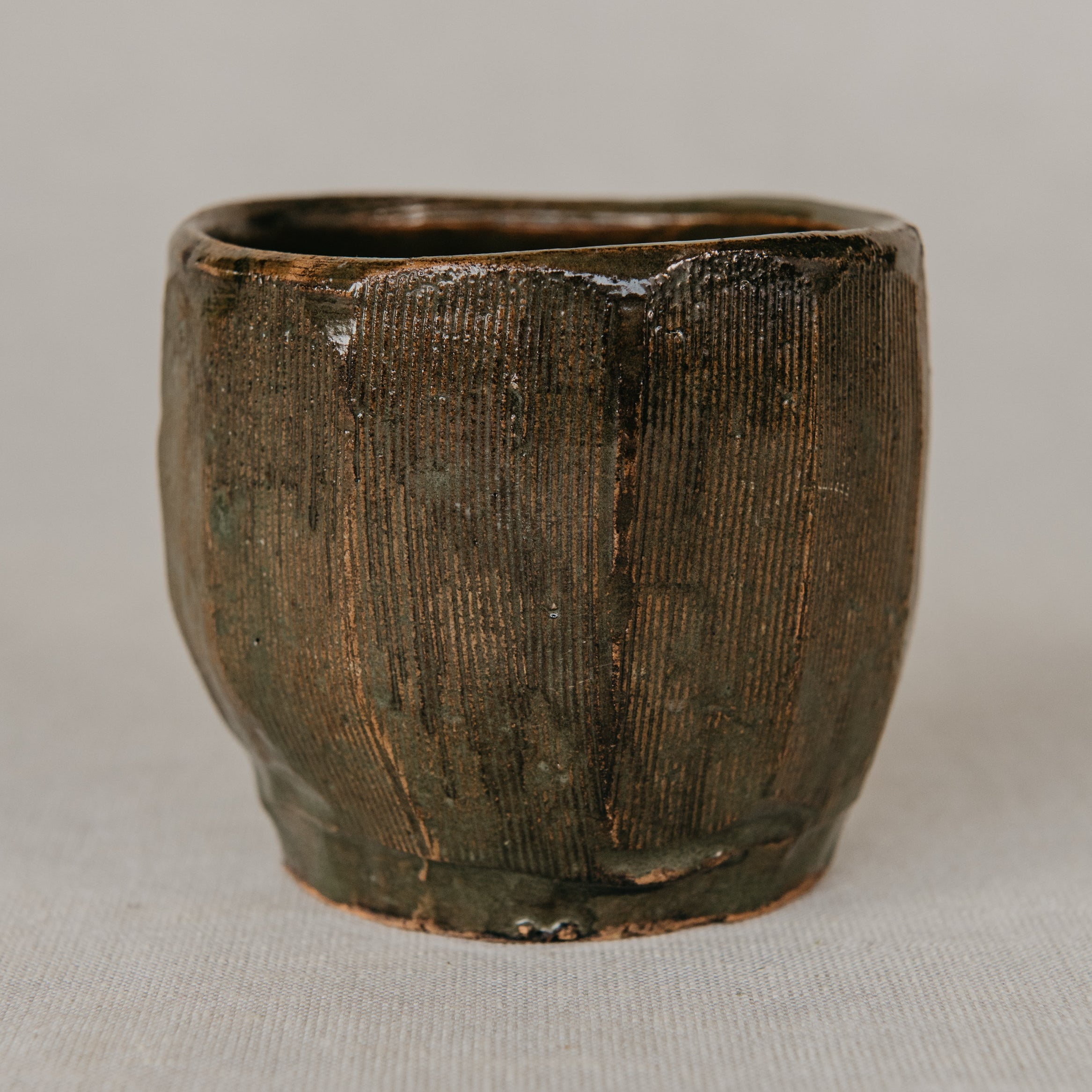 Brown ceramic cup with textured surface on a light gray background