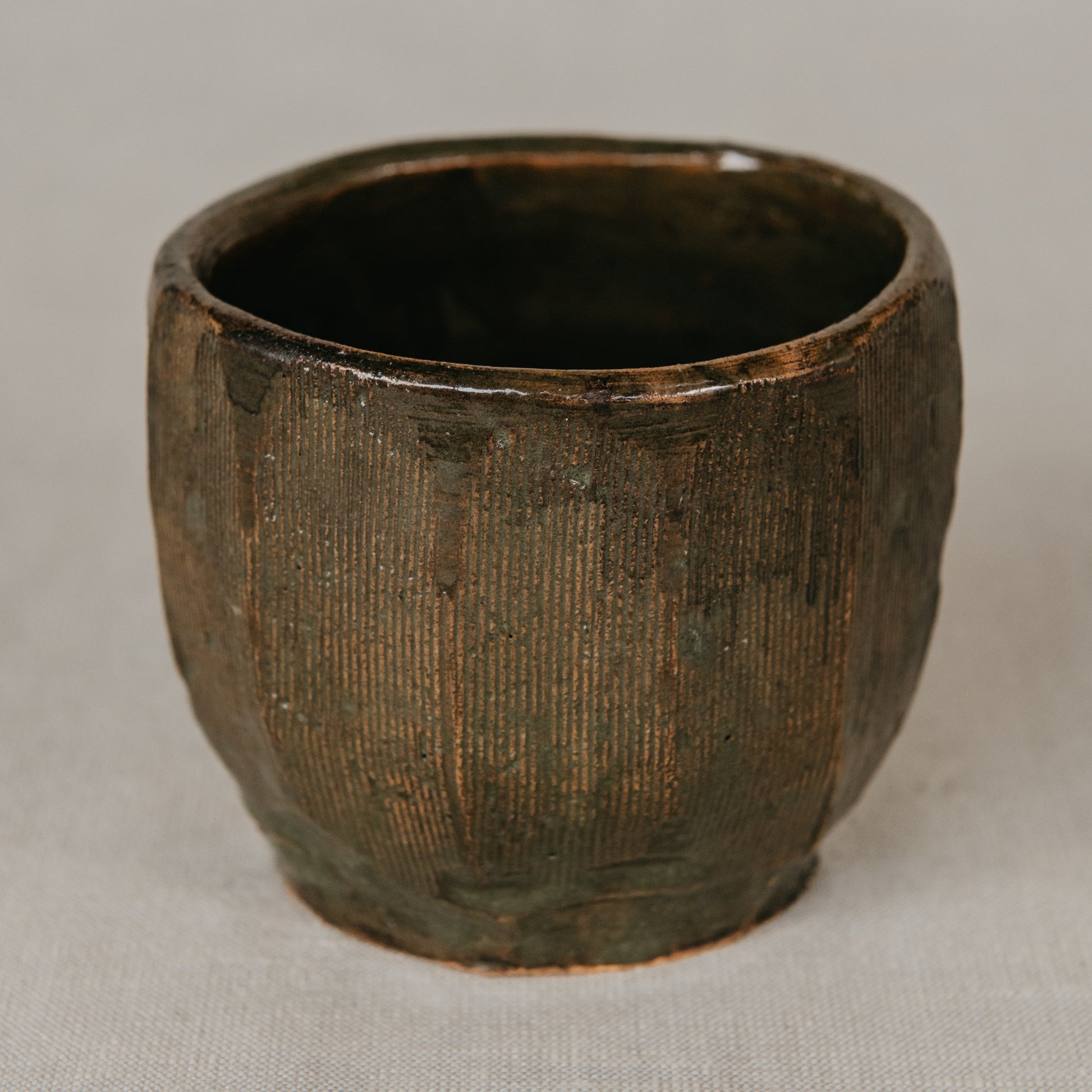 Dark brown ceramic cup on a light gray background