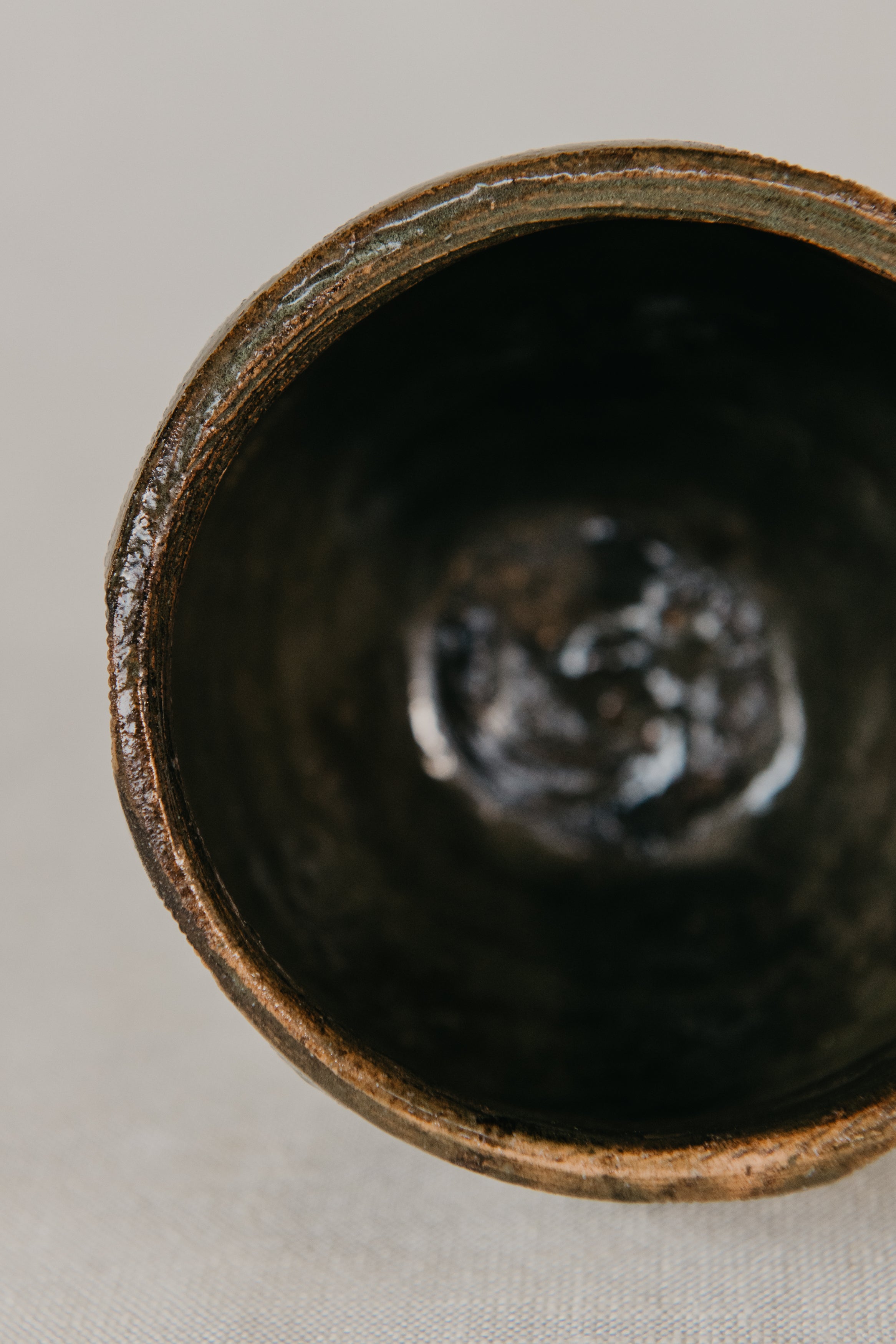 Close-up of a dark ceramic cup with a textured interior on a light background