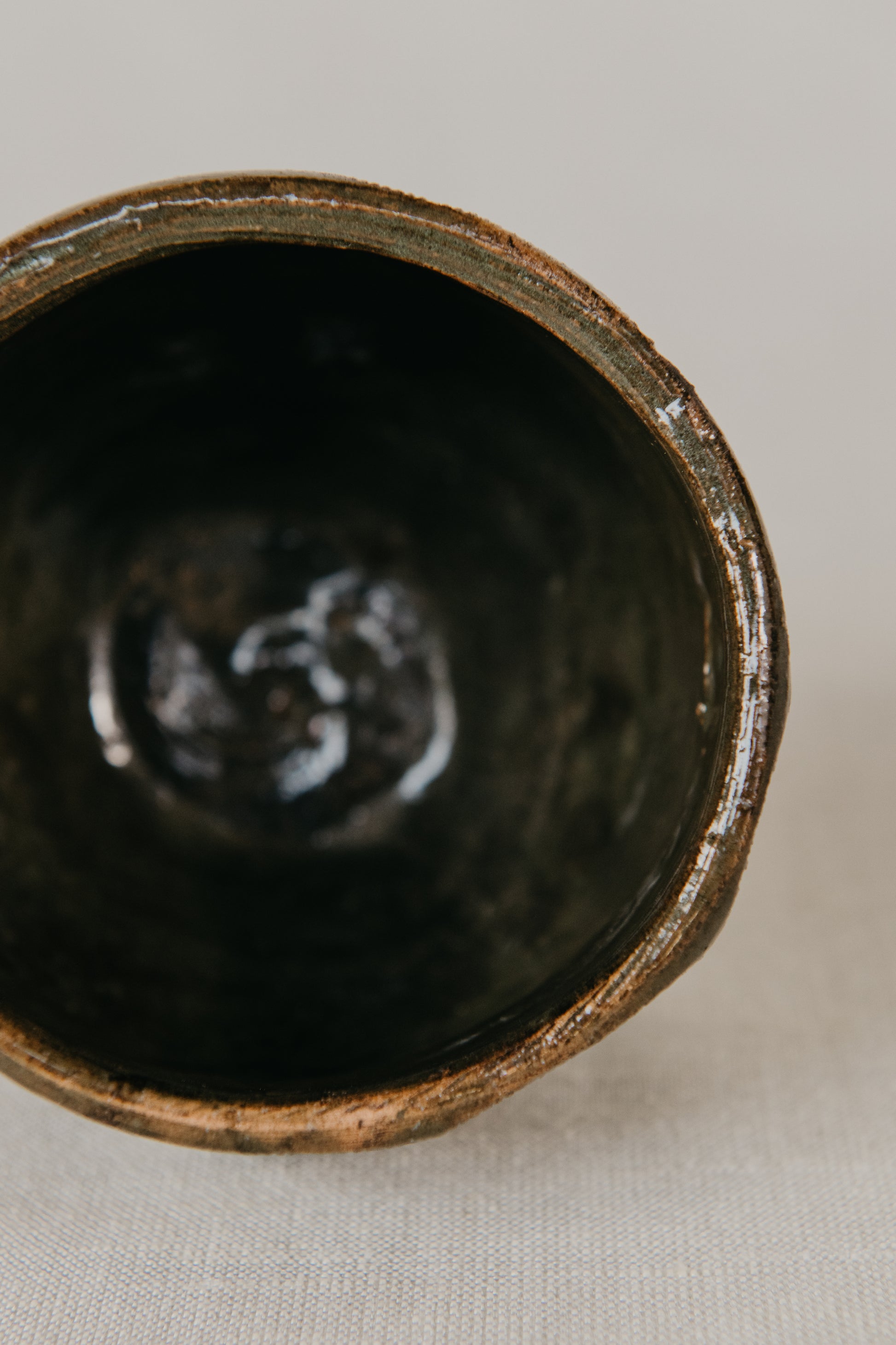 Close-up of a dark ceramic cup with a textured interior on a light background