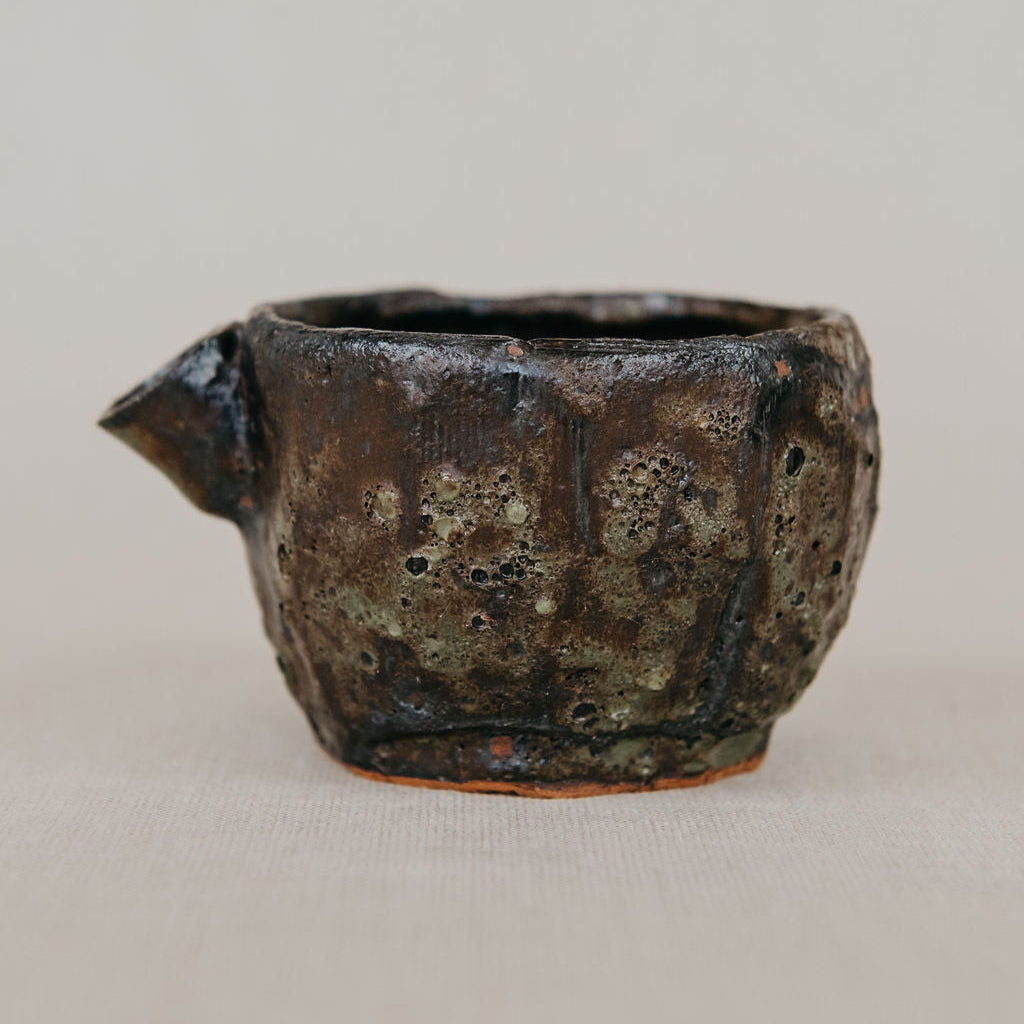 Vintage ceramic cup with a textured surface on a beige background