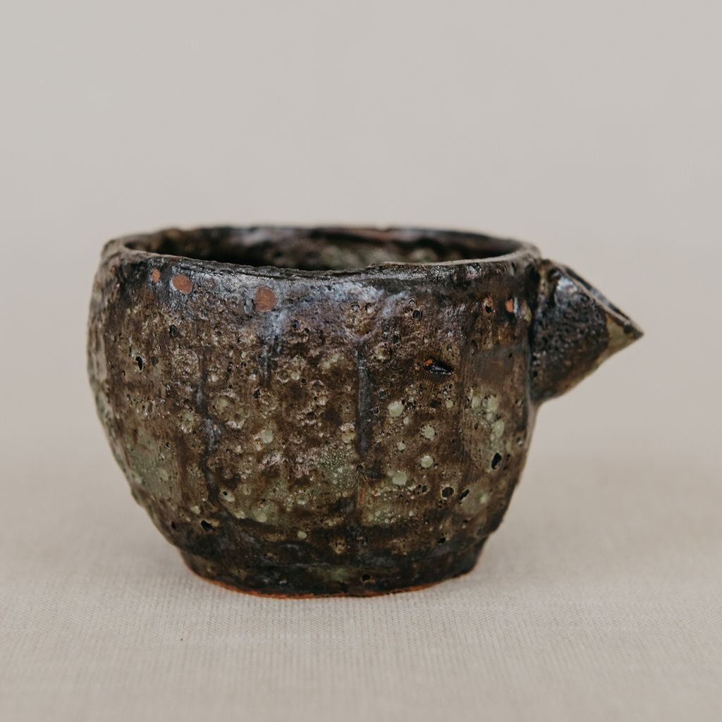 Ceramic cup with spout on a beige background