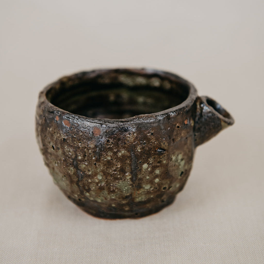 Brown ceramic cup with handle on a beige background