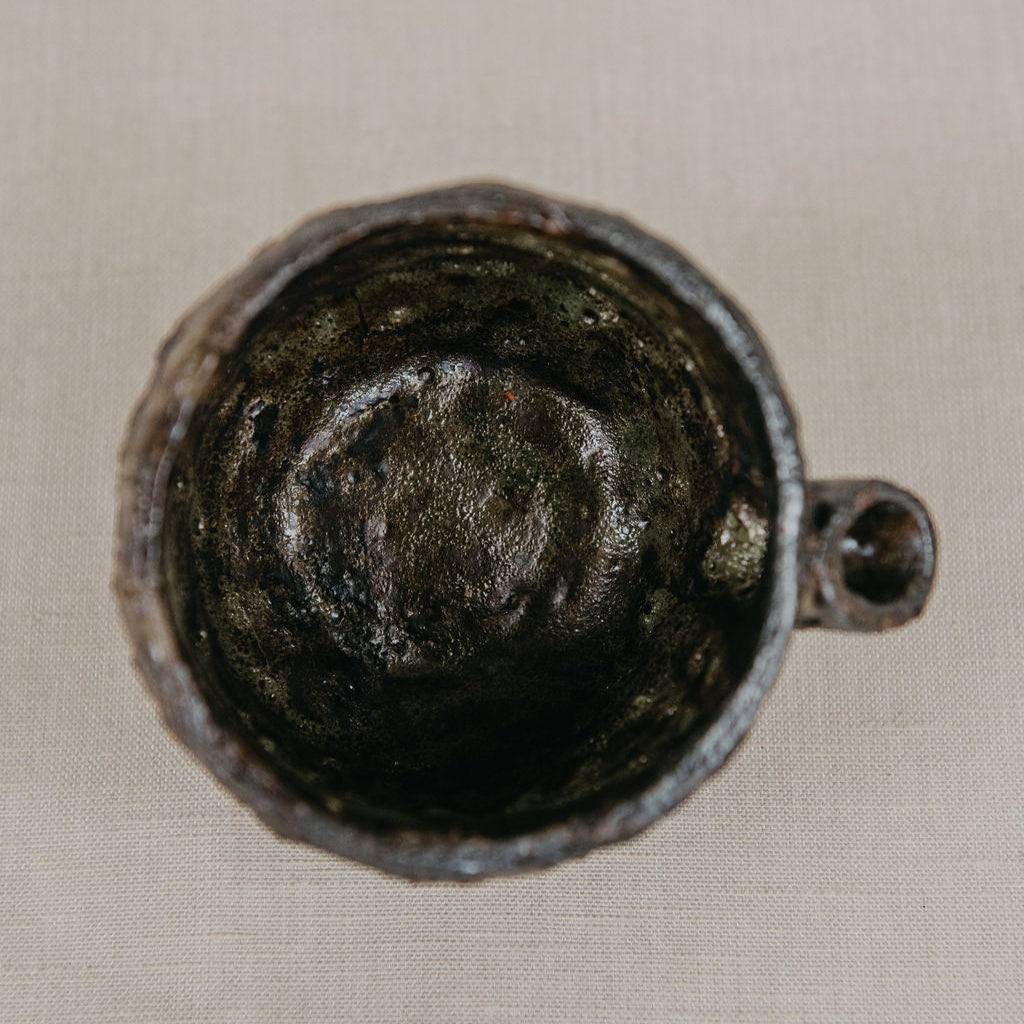 Close-up of a dark ceramic cup on a beige fabric background
