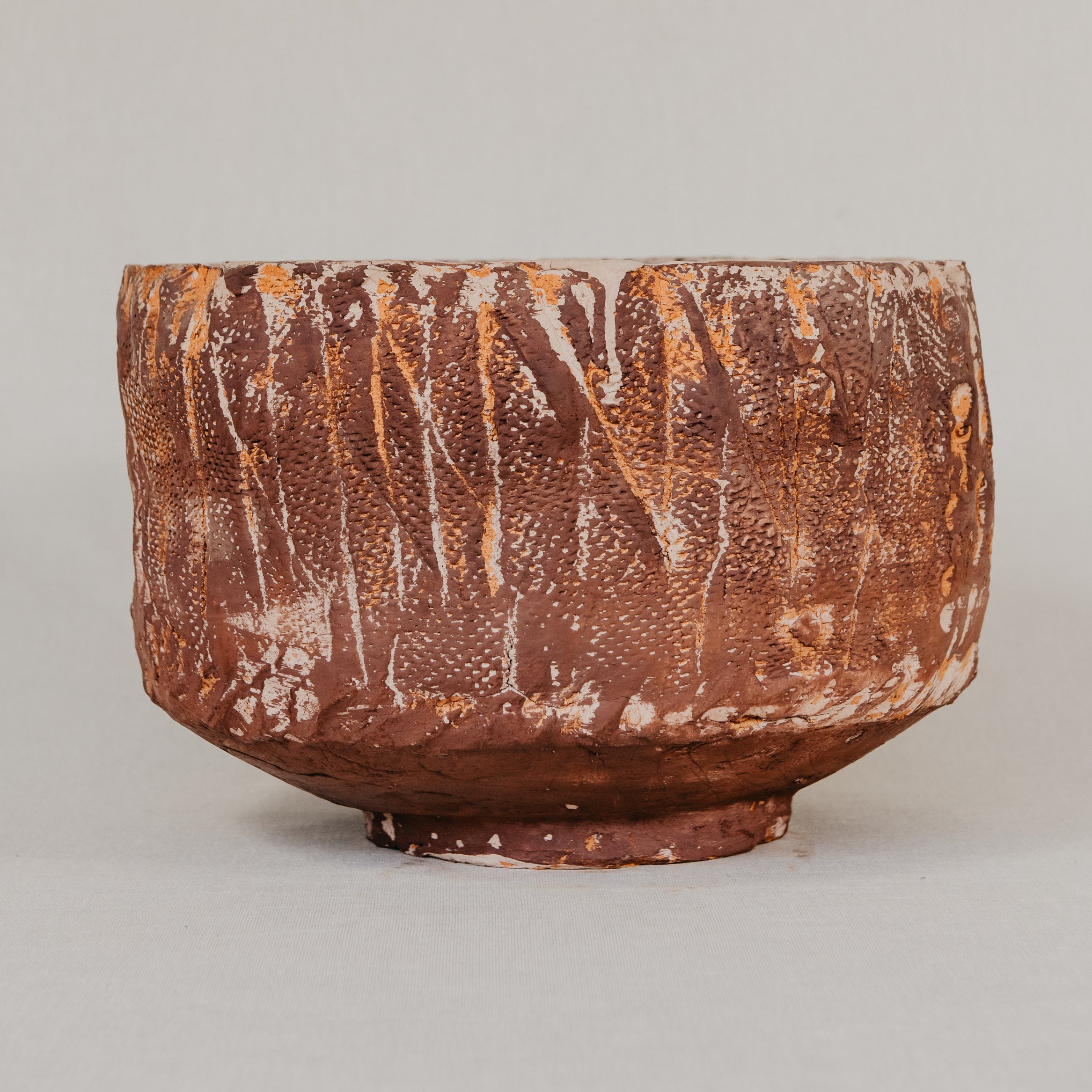 Brown ceramic bowl with textured surface on a light gray background
