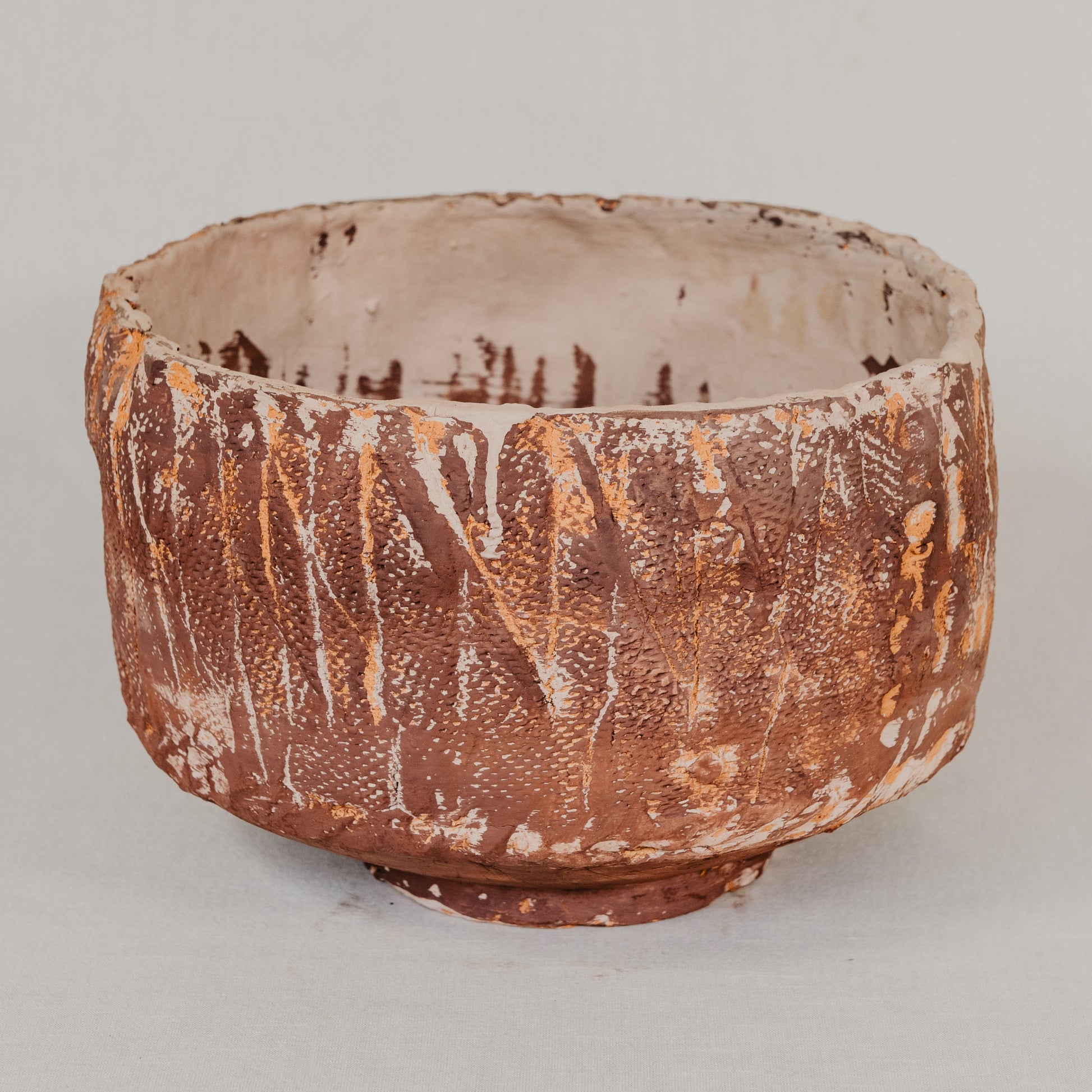 Terracotta pot with a textured surface on a light gray background