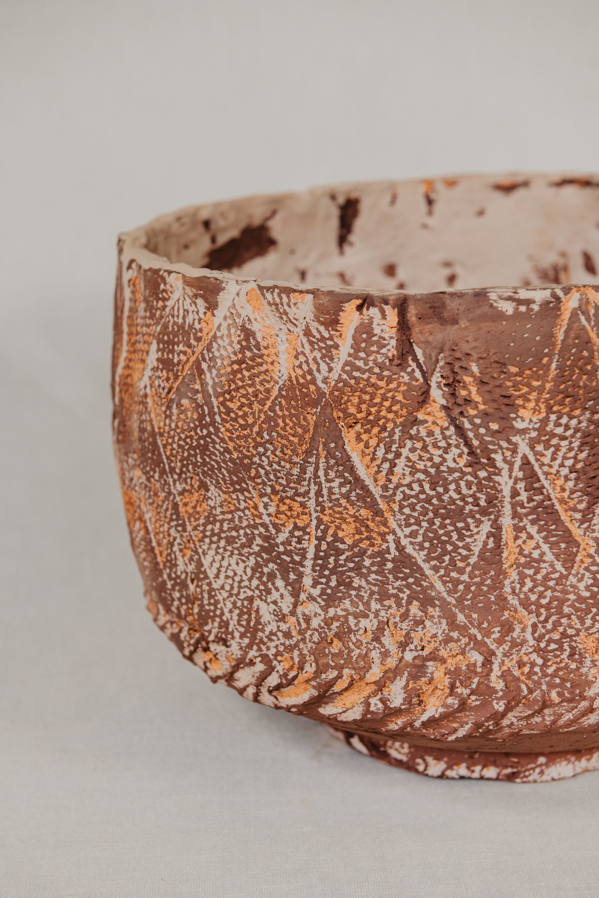 Ceramic bowl with textured brown and beige pattern on a light gray background