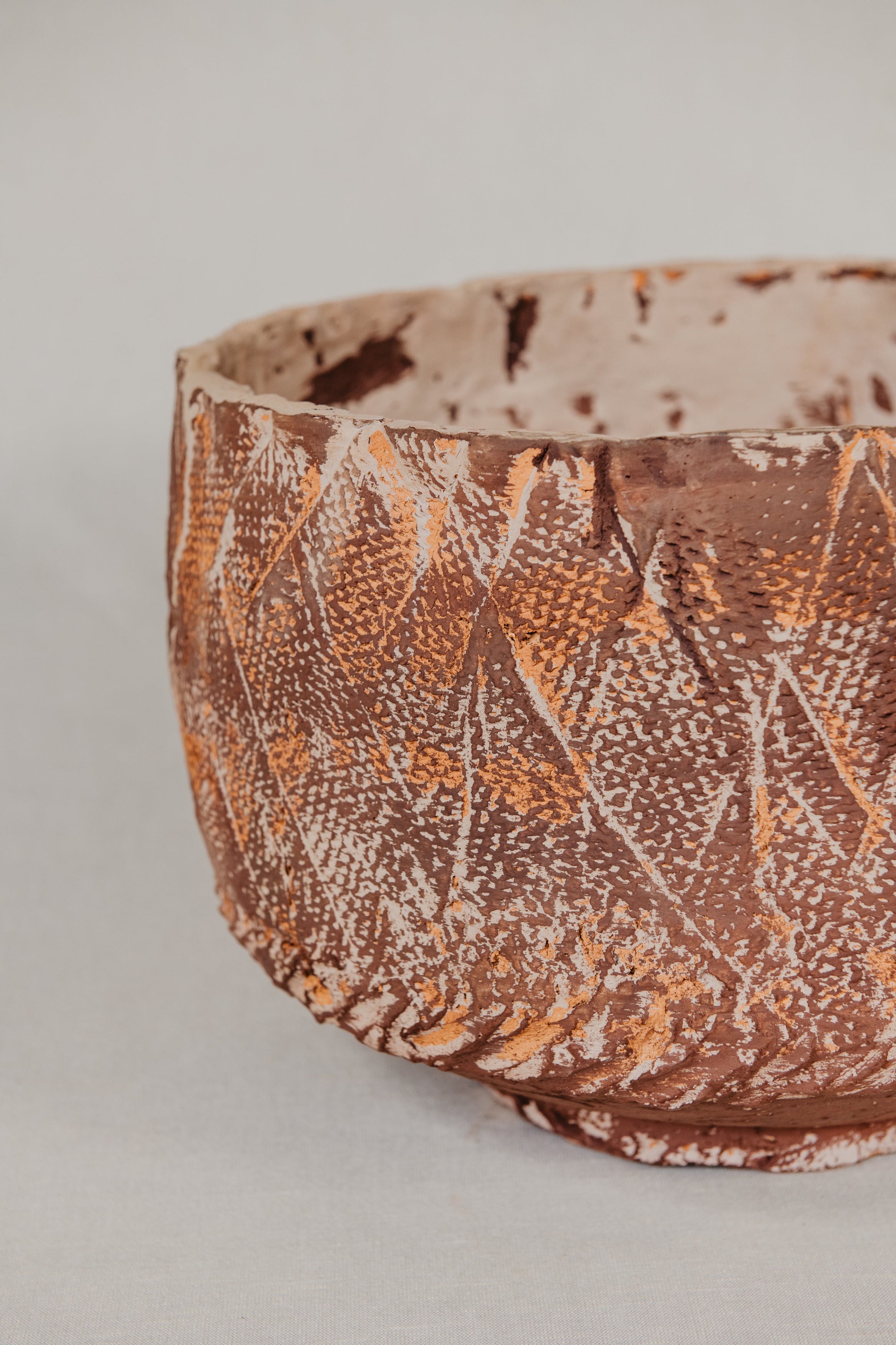 Ceramic bowl with textured brown and beige pattern on a light gray background