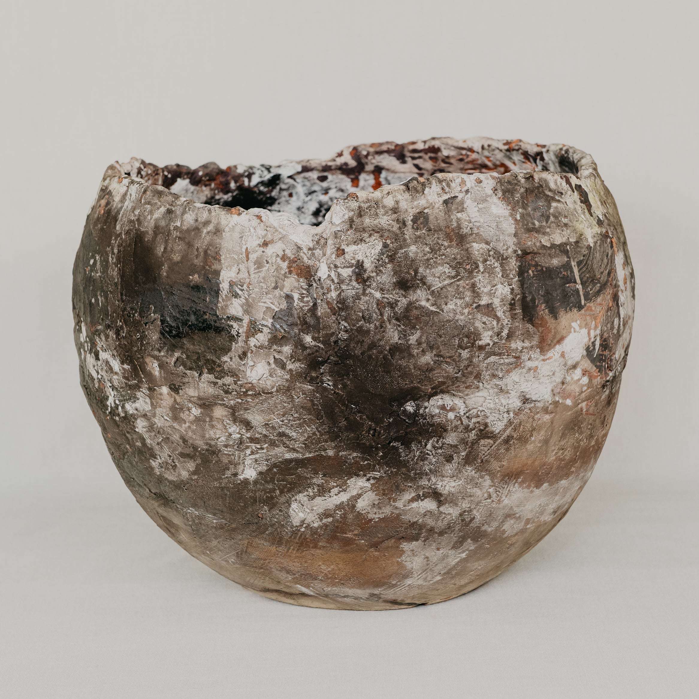 Vintage terracotta pot with a rough, textured surface on a plain background