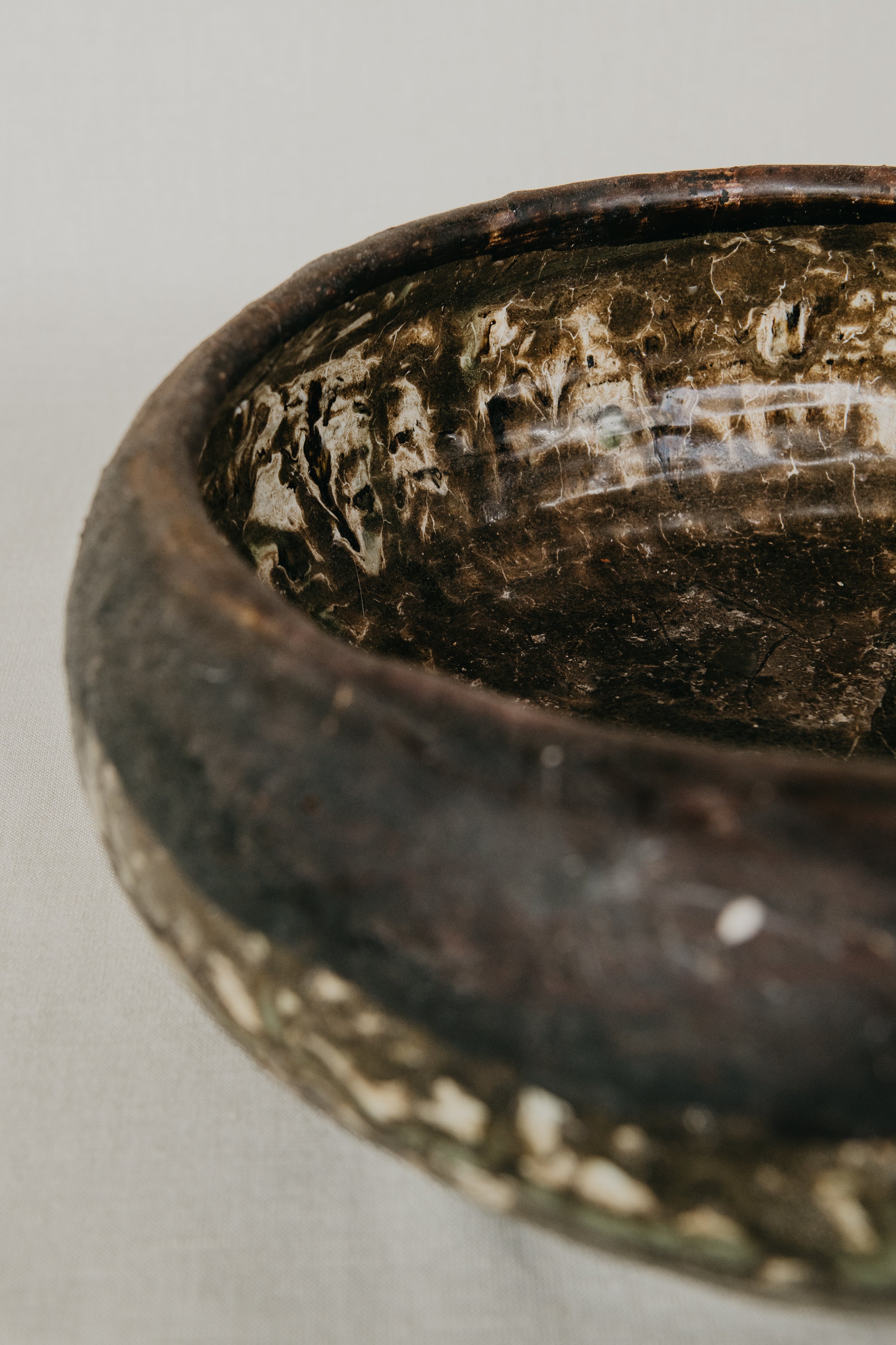 Close-up of a dark brown ceramic bowl with engraved text on a light gray background