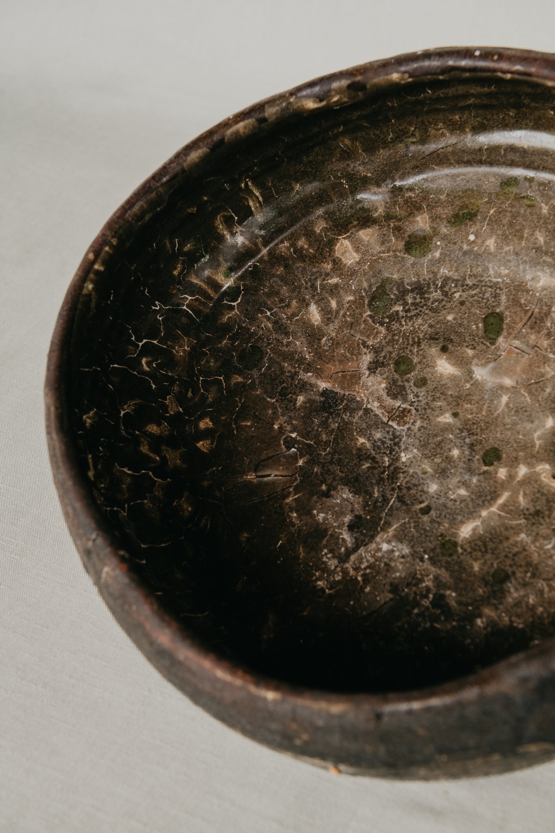 Close-up of a dark ceramic bowl with a textured interior on a light gray background