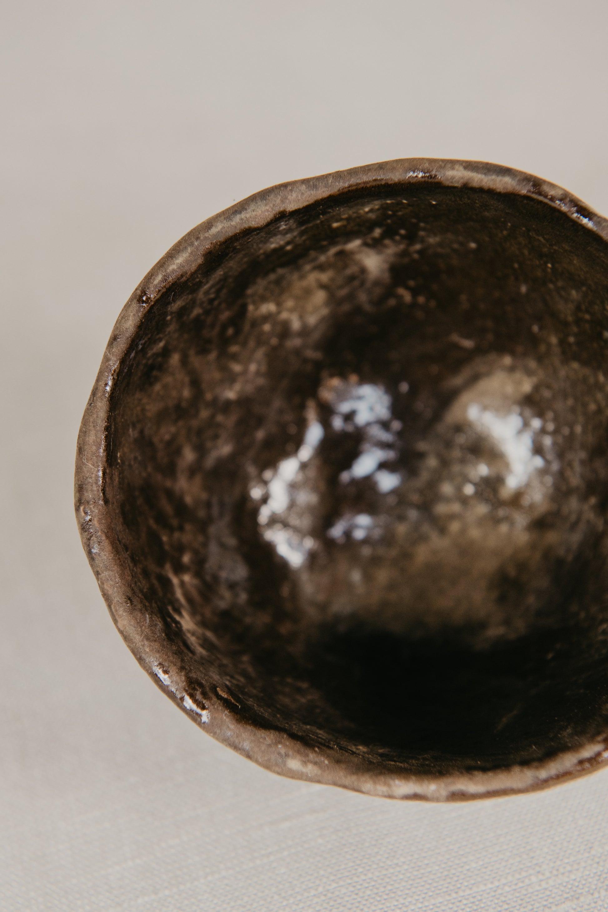 Close-up of a dark brown ceramic bowl on a light gray background