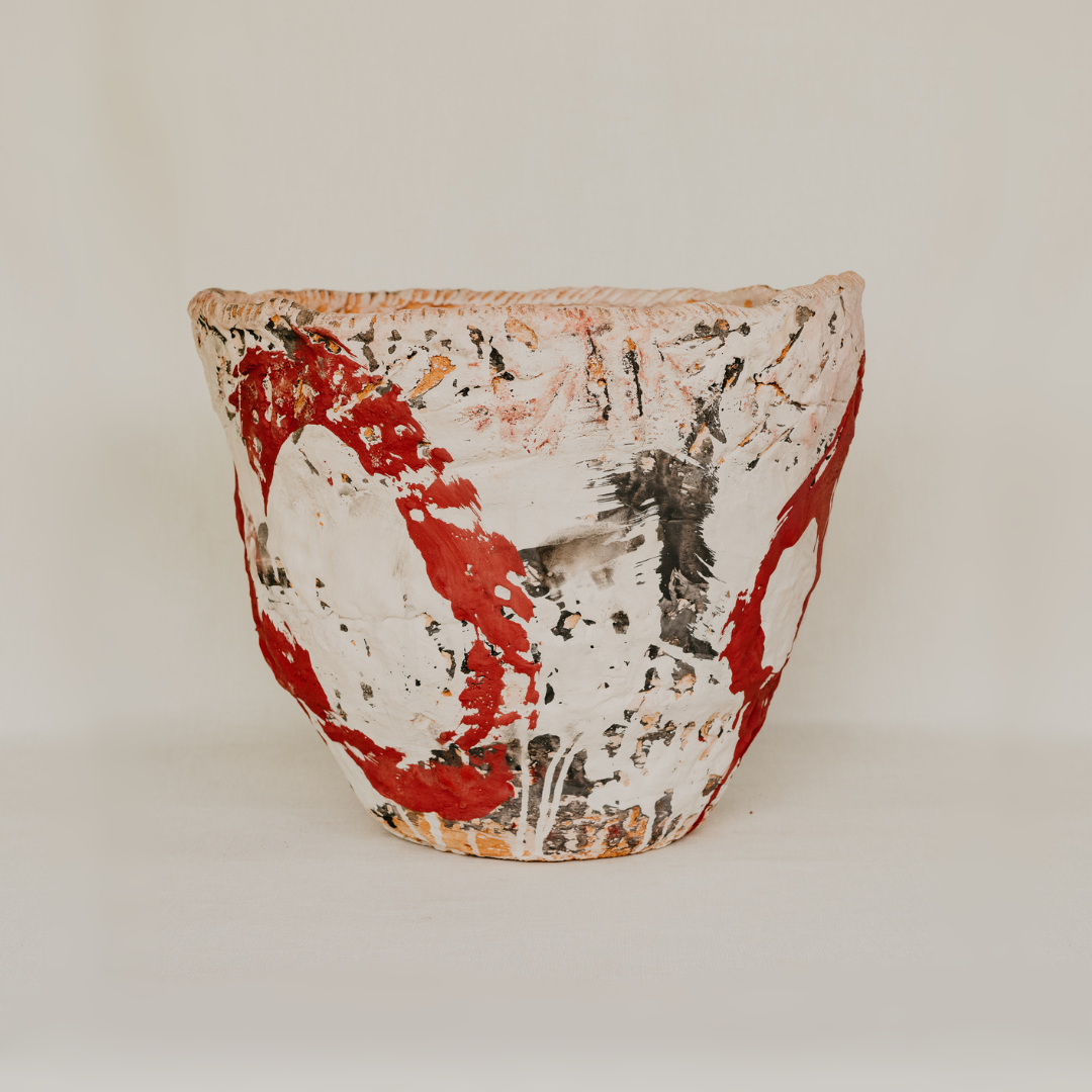 Ceramic pot with abstract red and black design on a white background