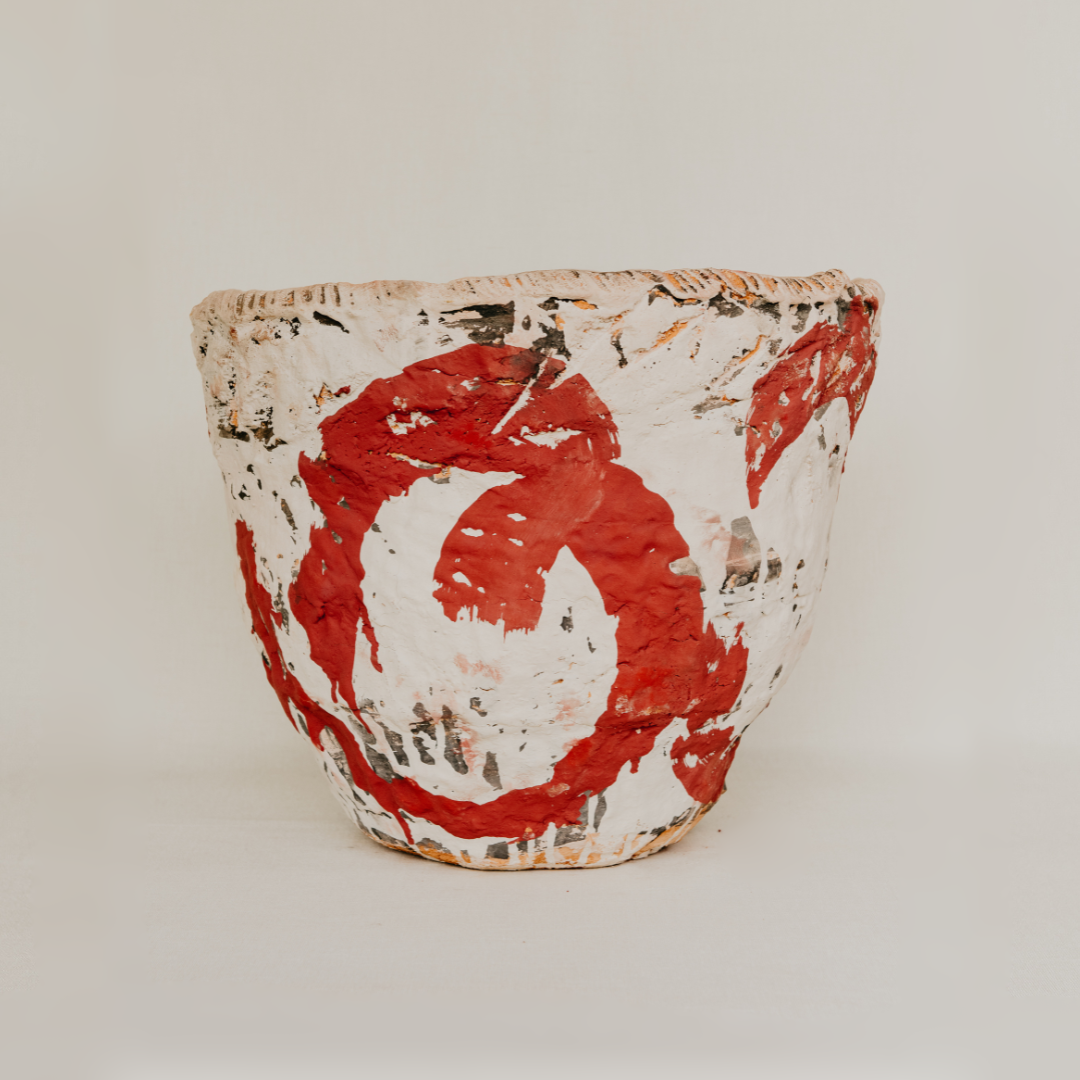 Ceramic pot with red and white abstract design on a beige background