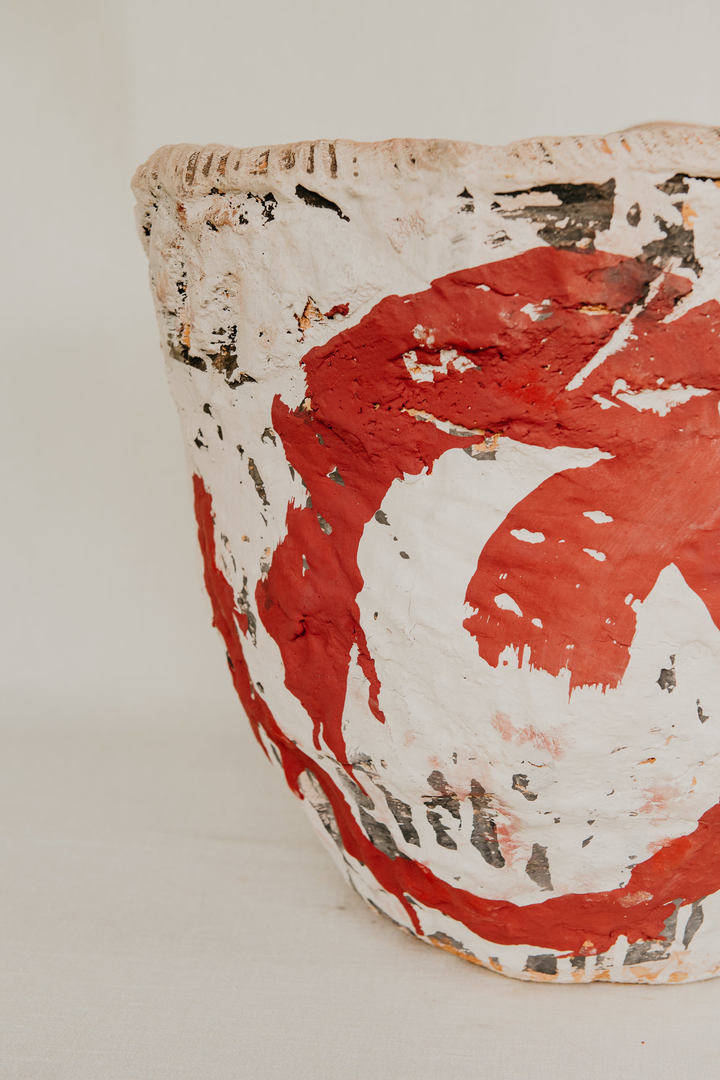 Ceramic pot with red and white abstract design on a light background
