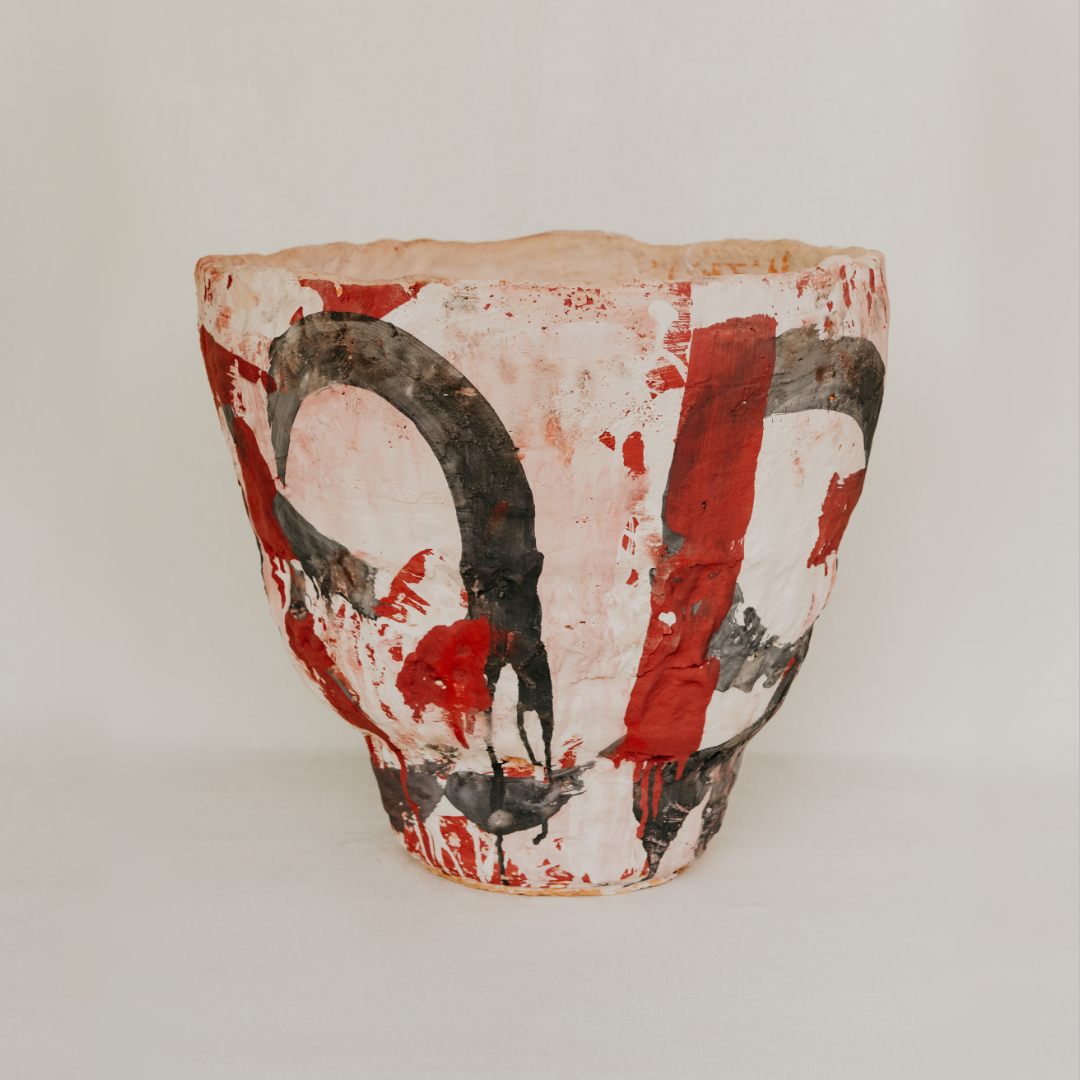 Decorative pot with red and black abstract design on a light background
