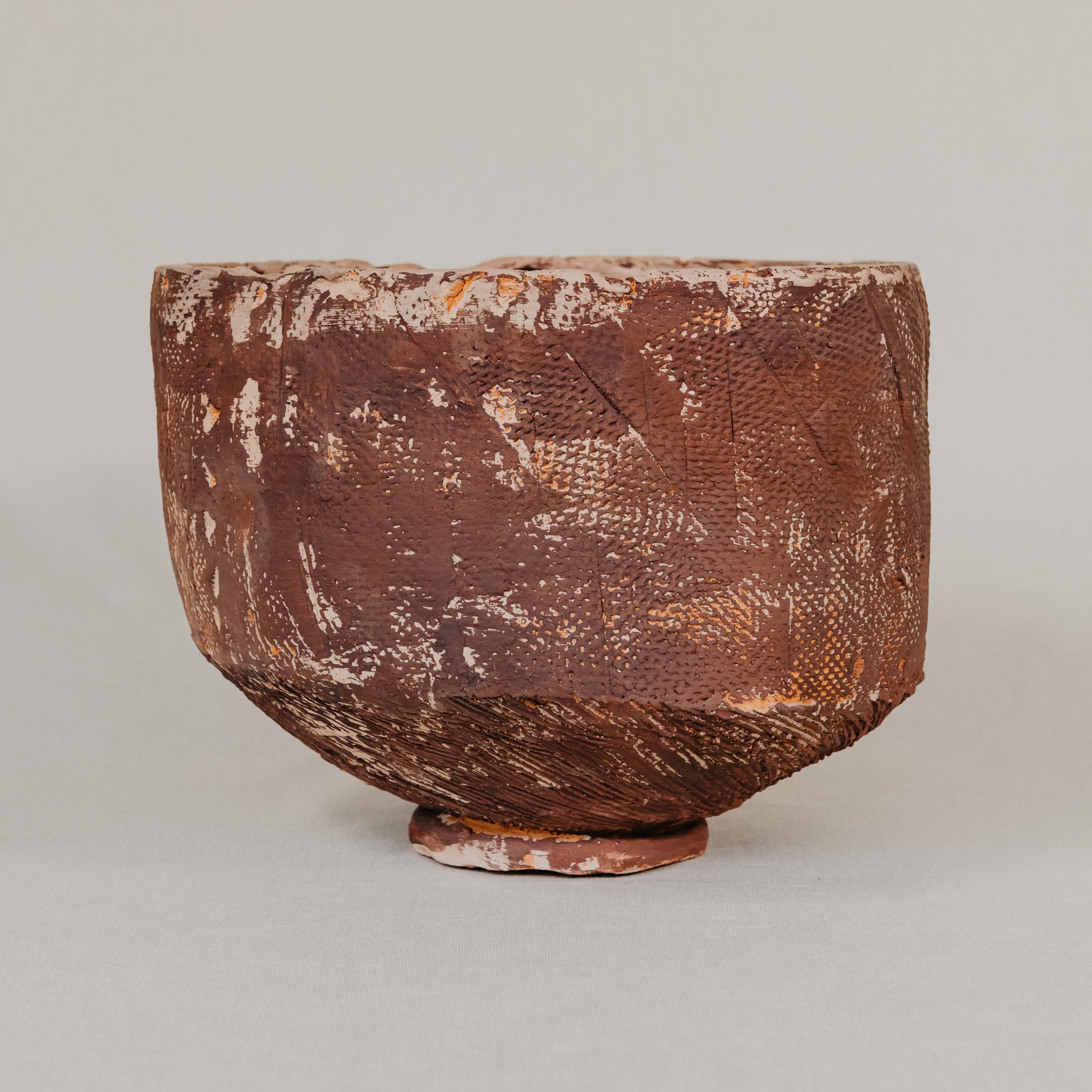 Brown ceramic bowl with textured surface on a light gray background