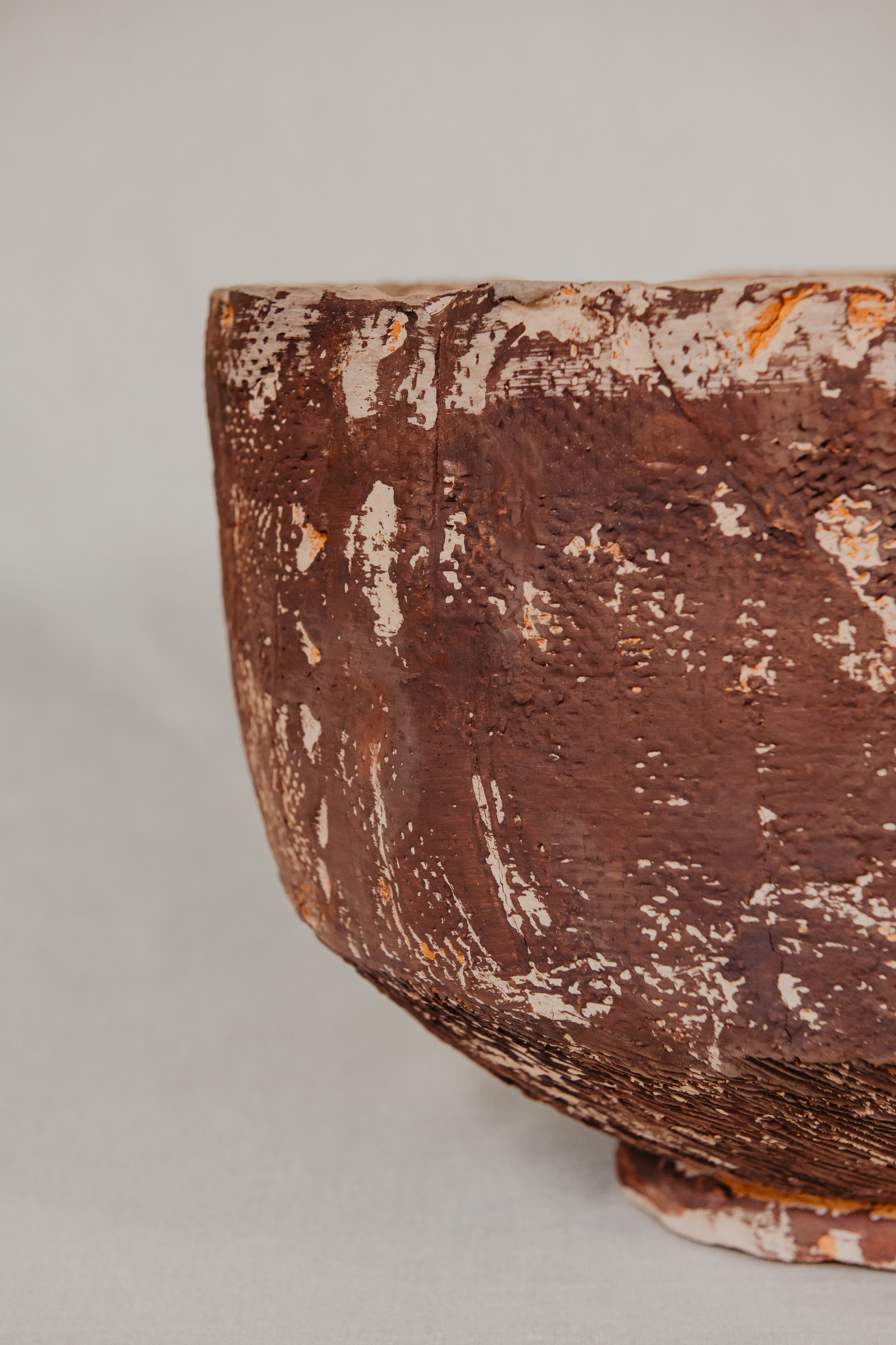 Close-up of a textured brown ceramic bowl on a light gray background