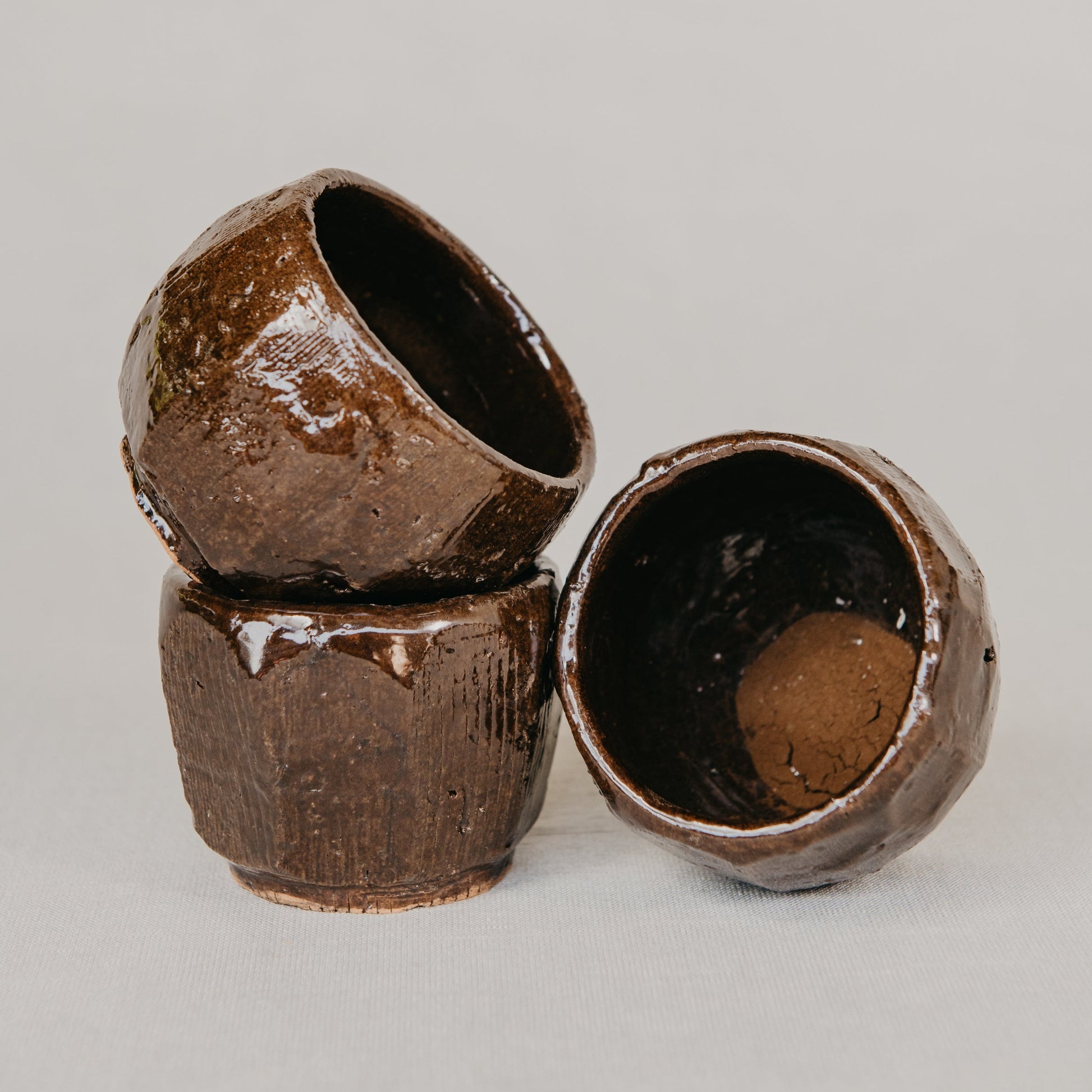 Three brown ceramic cups on a gray background