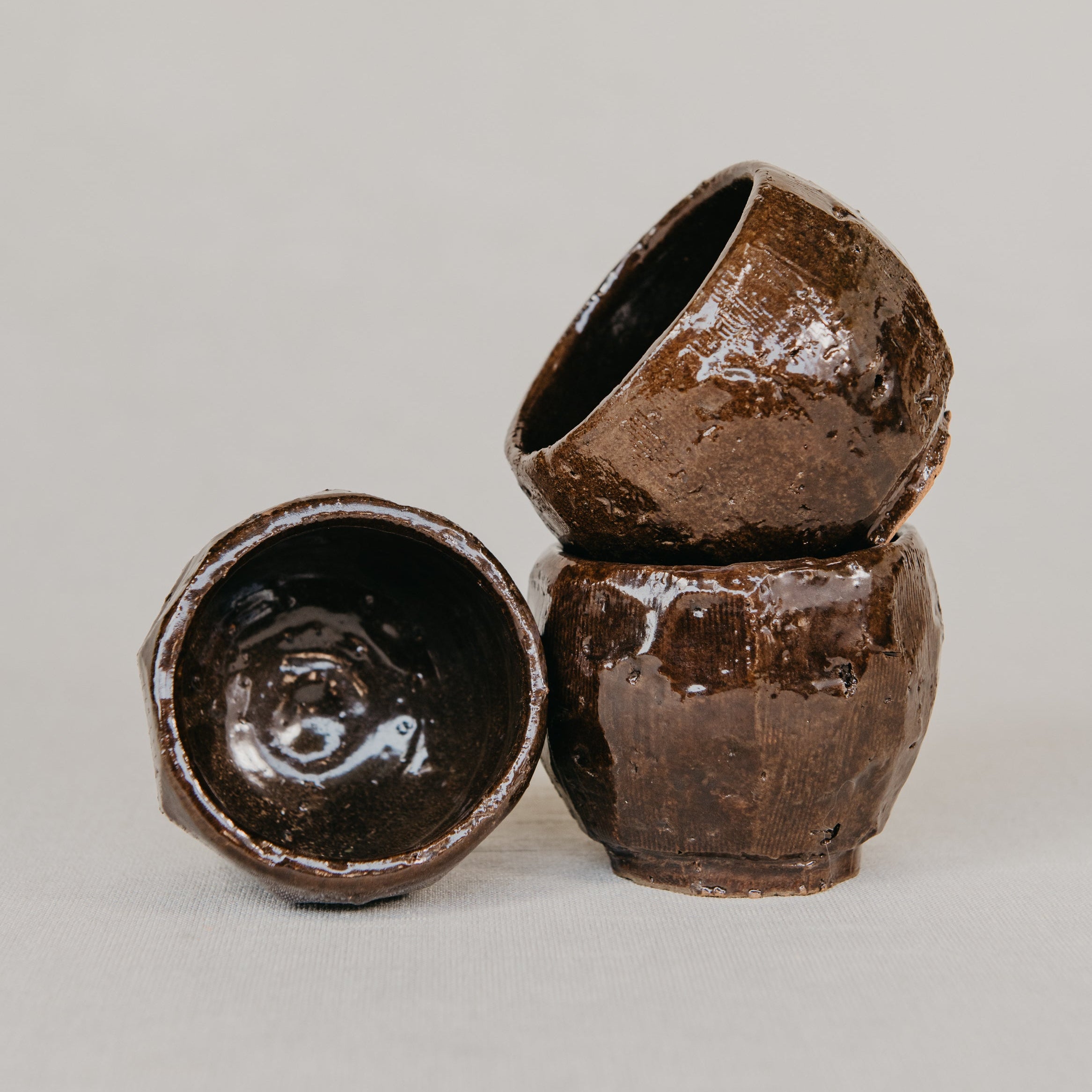Three brown ceramic bowls stacked on a light gray background