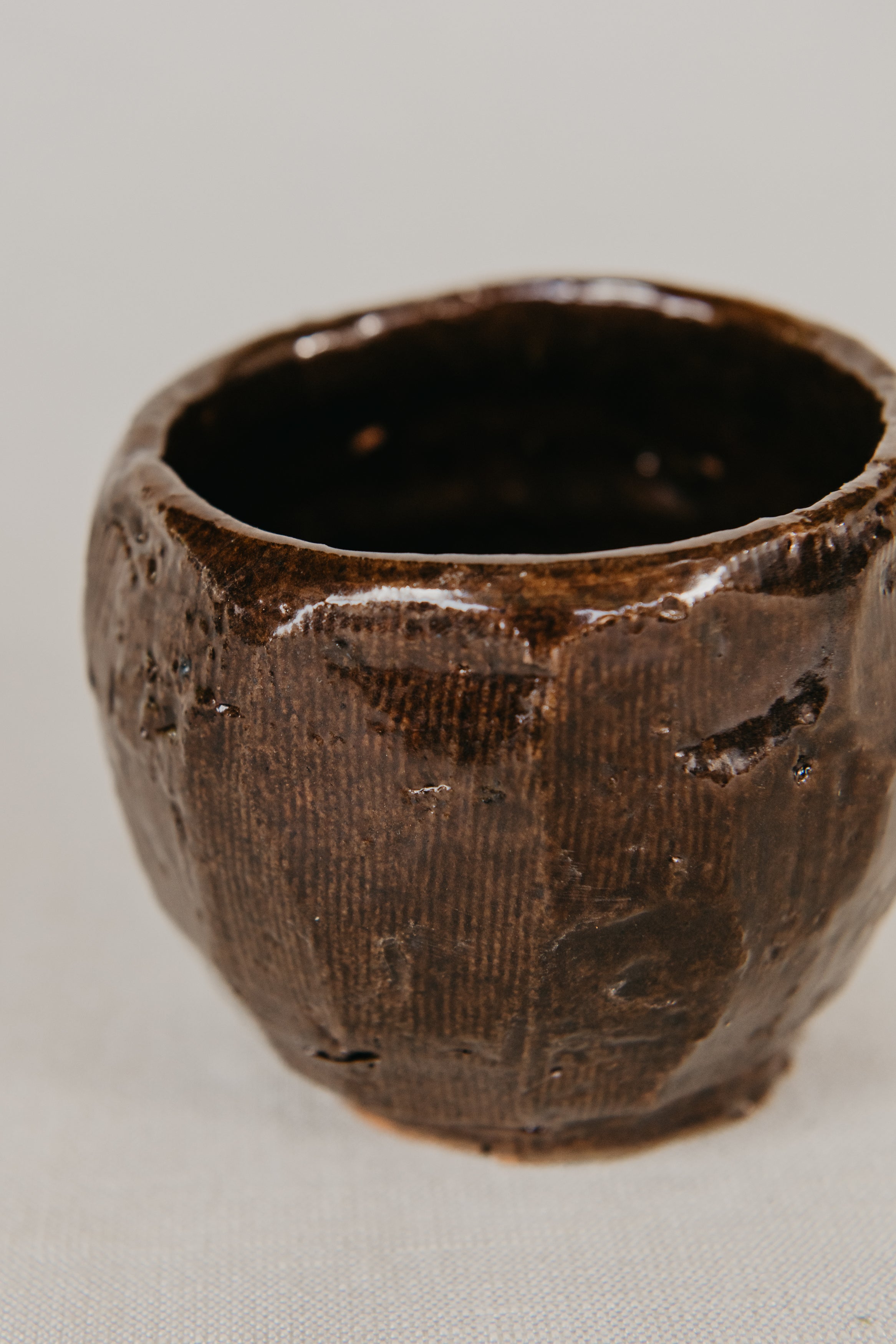Brown ceramic cup with textured surface on a light gray background